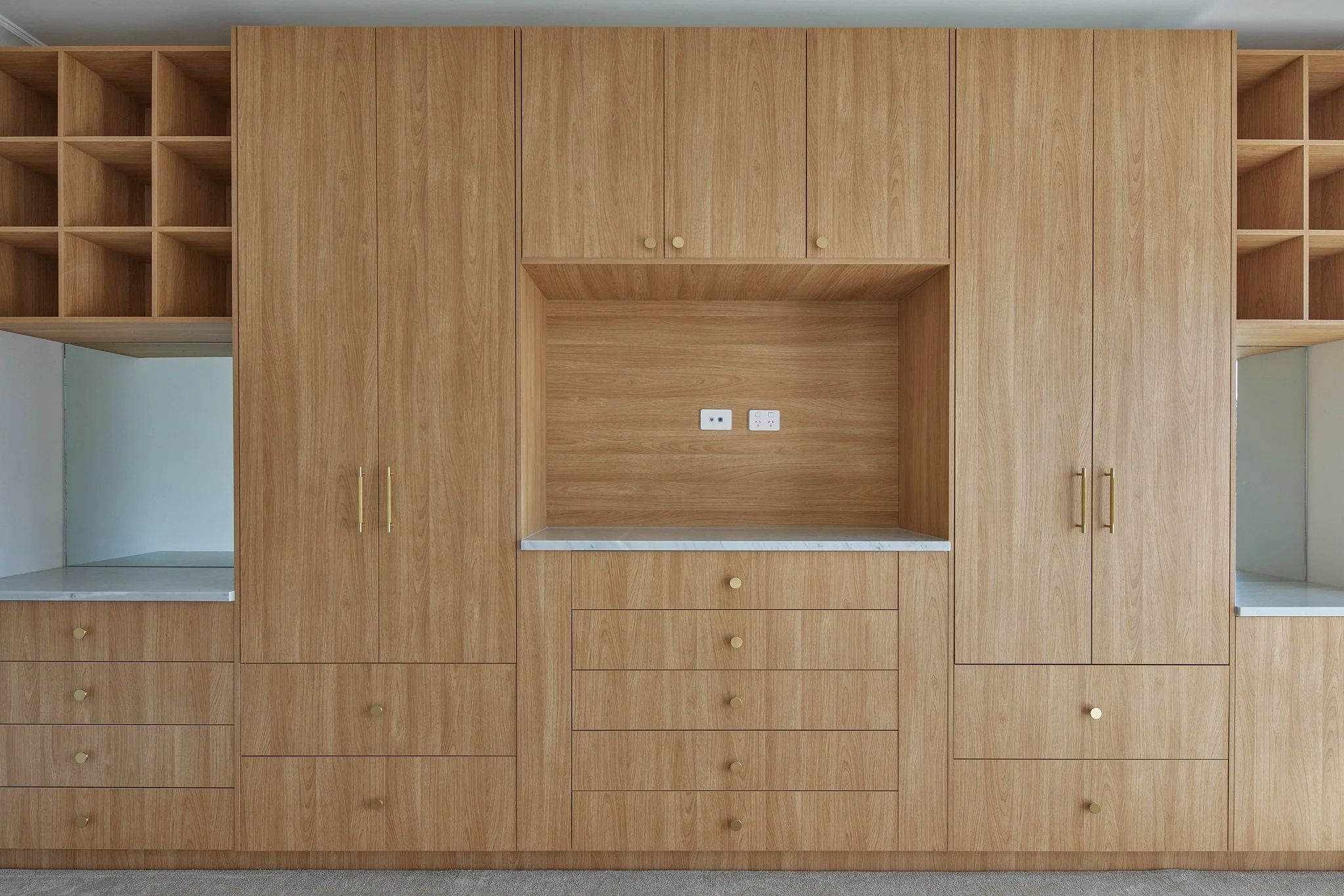 Wooden built-in closet with cabinets, drawers, and open shelves in a room.