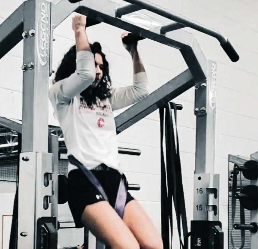 Person doing pull-ups at the gym using an assisted pull-up machine.