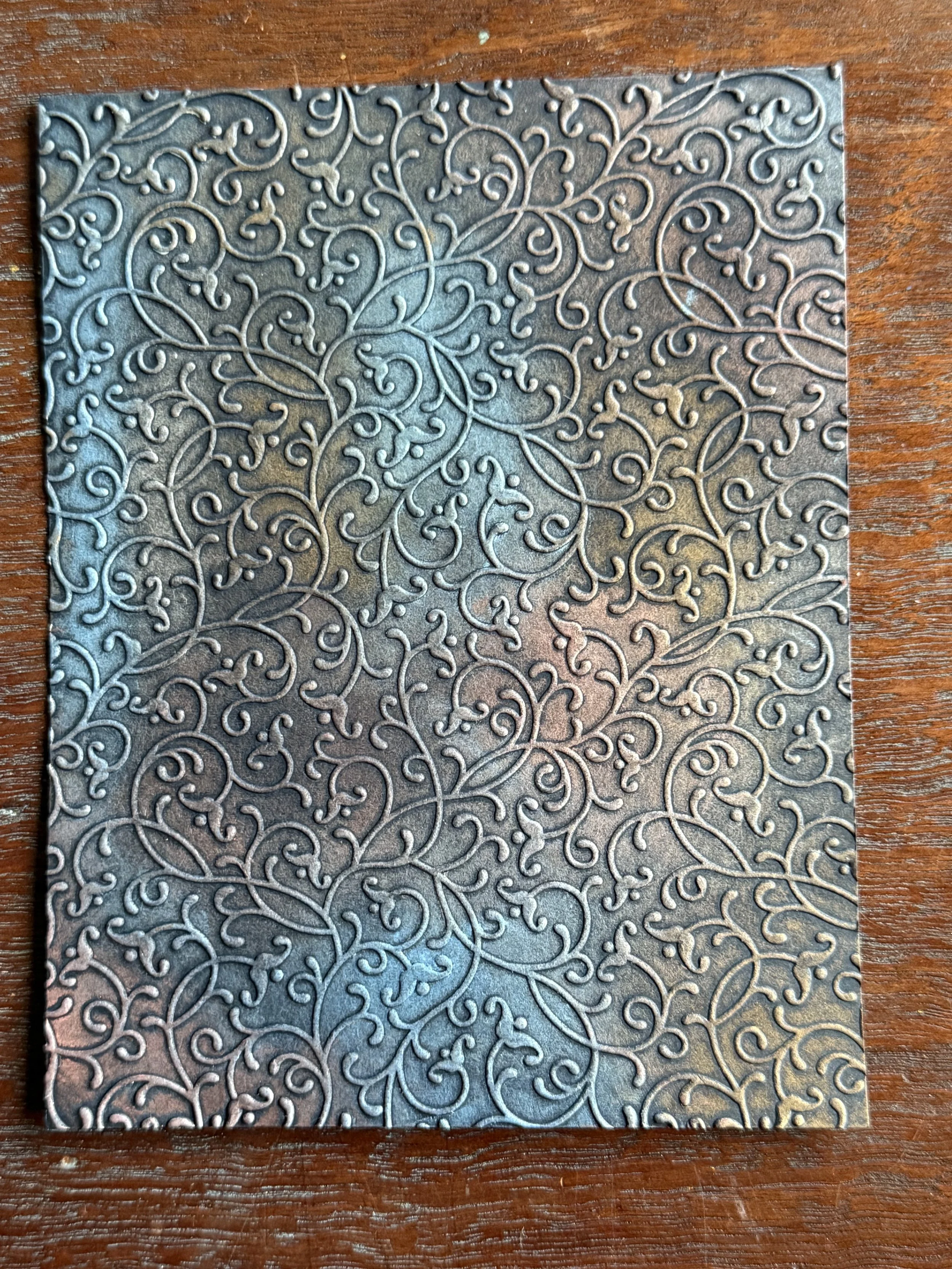  This background was made using Gina K Designs Petite Flourish embossing folder. I then randomly added Metallic Rub-Ons in the following colours: Walnut, Rosewood, Silver Blue, and Iris. This gives the panel a vintage look so I’ll continue with that 