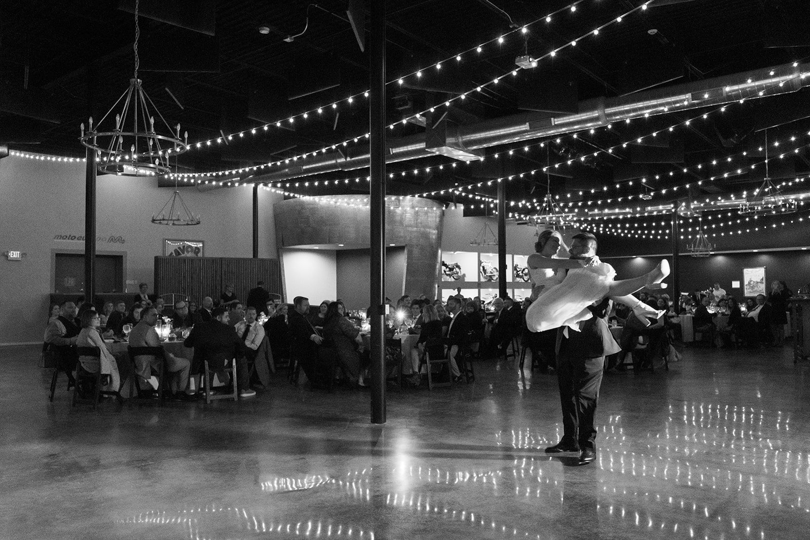 smith and company interior event space at the moto museum event venue st. louis showing vintage motorcycles in the background and a bride and groom doing their first dance at their wedding