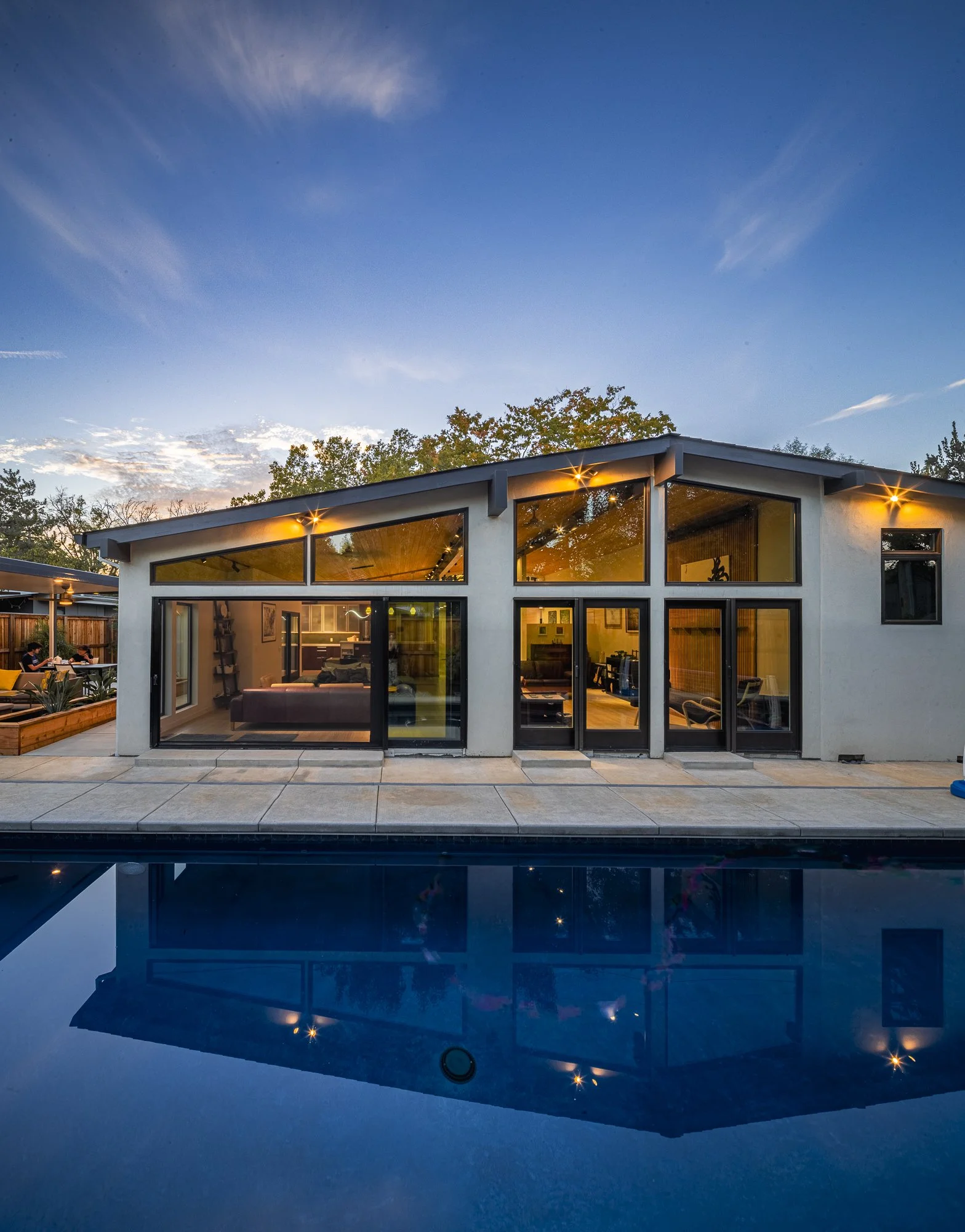 The long pool stretches along the back, accessible from the interior great room through large sliding doors.