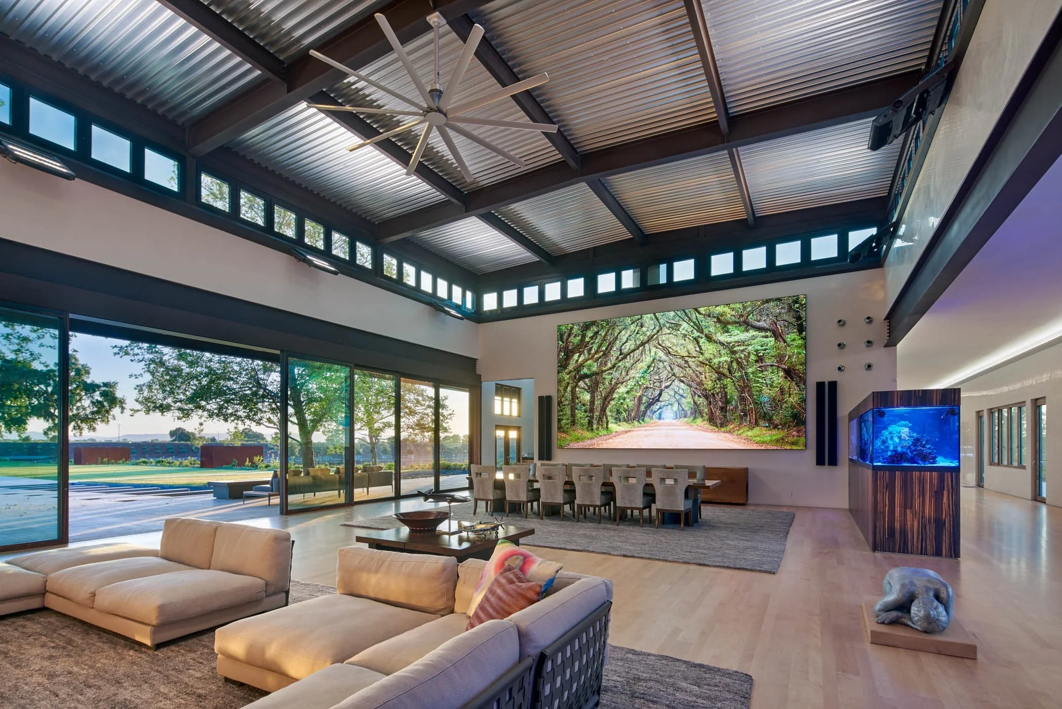 In the great room, the side wall supports the largest residential video screen ever installed at the time. Two giant saltwater fish tanks frame the entry, separating the hallway from the great room.