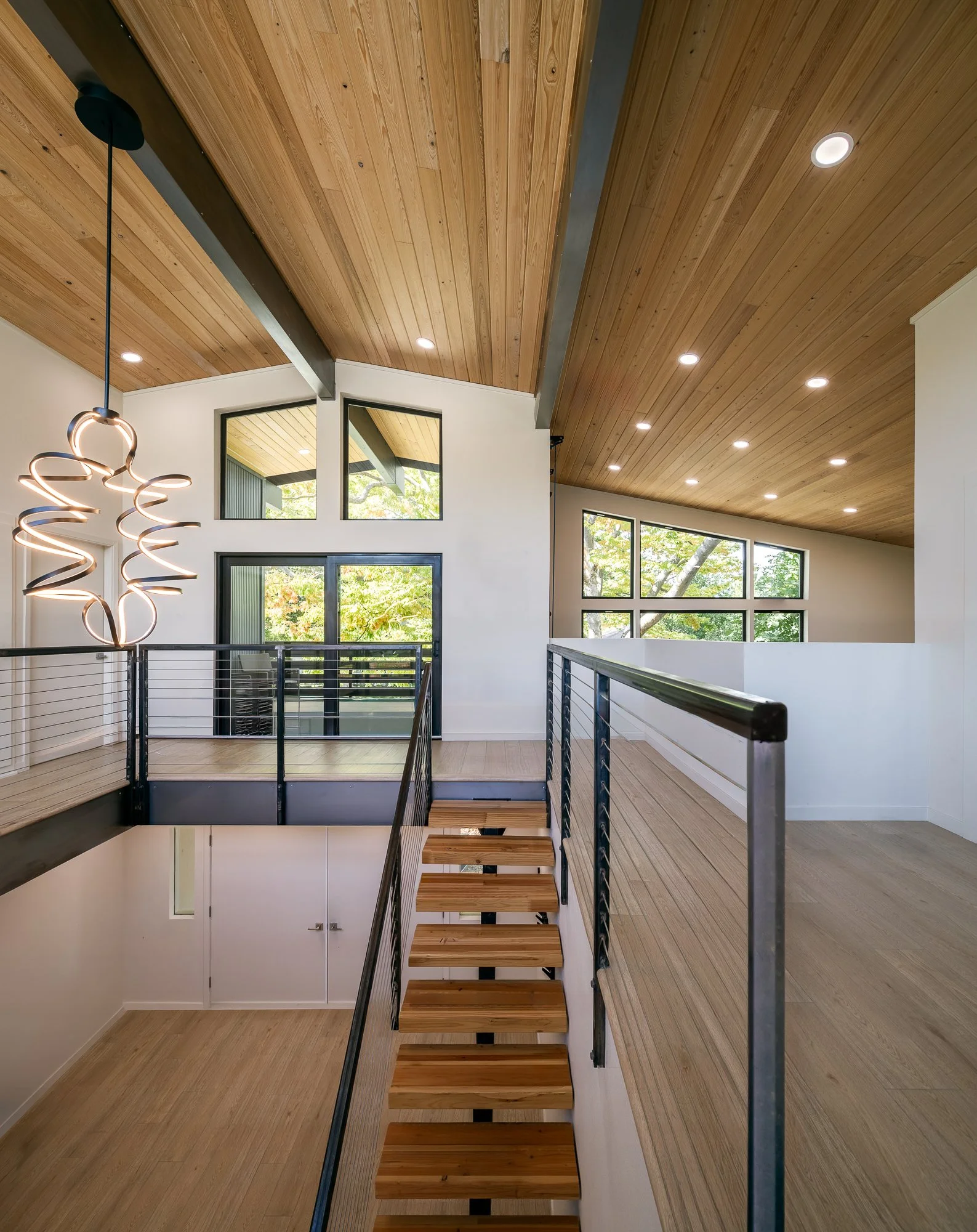 The upper level opens onto an elevated private deck and an interior double-height climbing wall in the open game room.