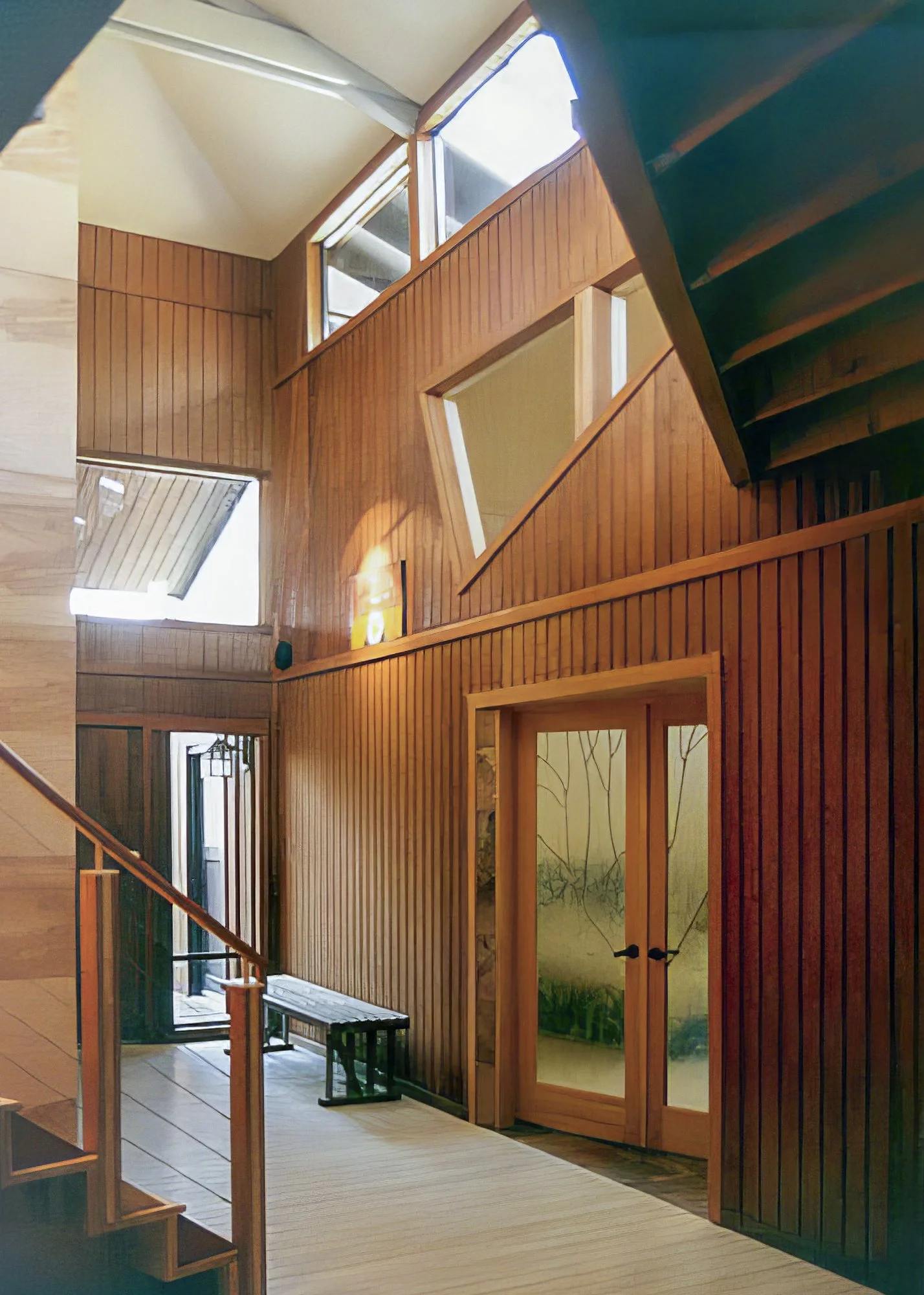 The interior entrance walls feature wood paneling and non-traditional window shapes that form a dialogue with the atrium steps.