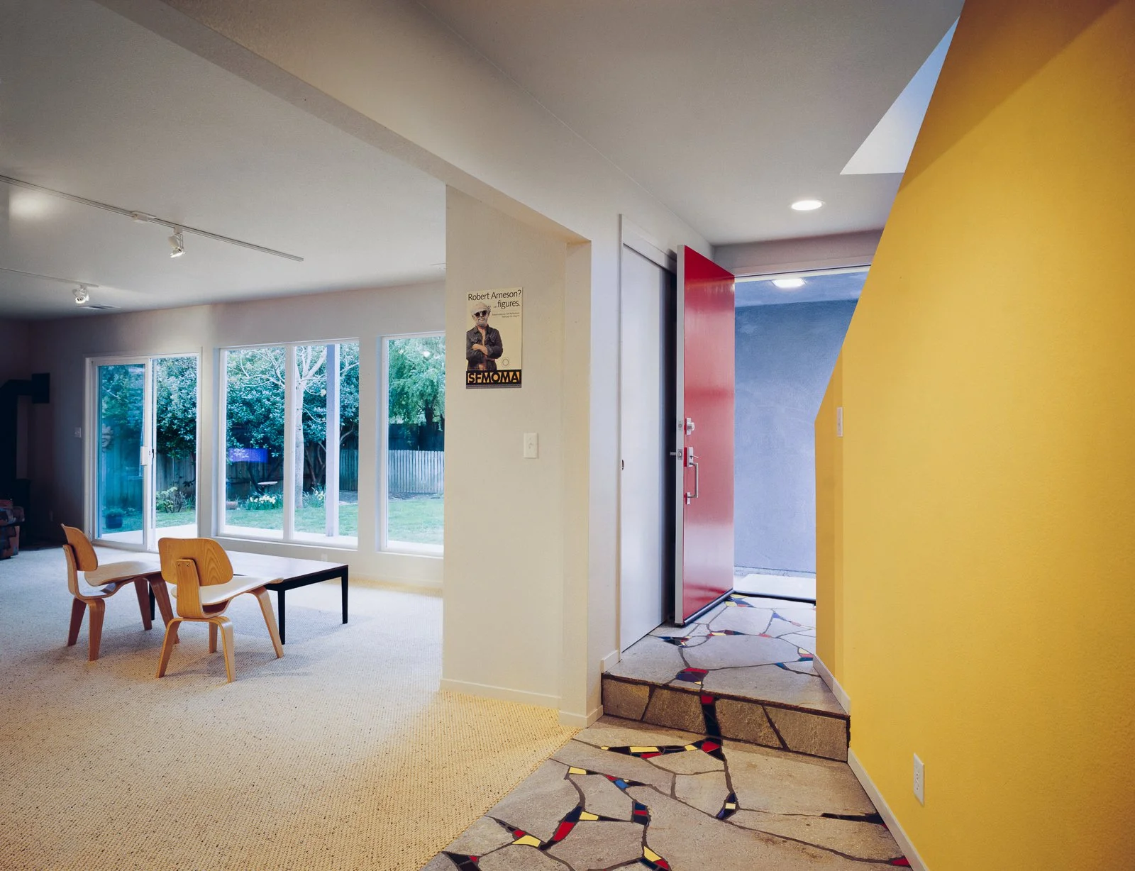 The new family room is a communal space where the generations can be together. It features a wall of windows looking out onto the backyard. Flagstone pavers and colorful ceramic tiles are broken and rearranged in mosaic forms, connecting to the famil