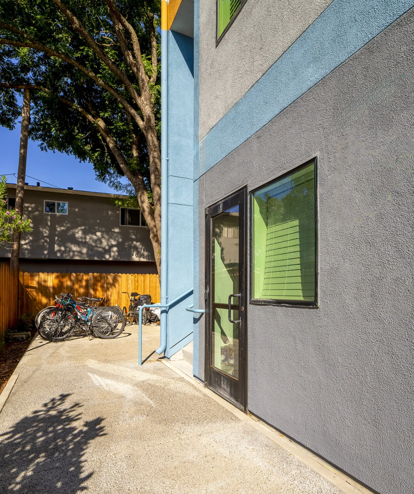 The California-sky-blue second floor provides transitional housing with shared living spaces. It has a private entrance on the building's side.