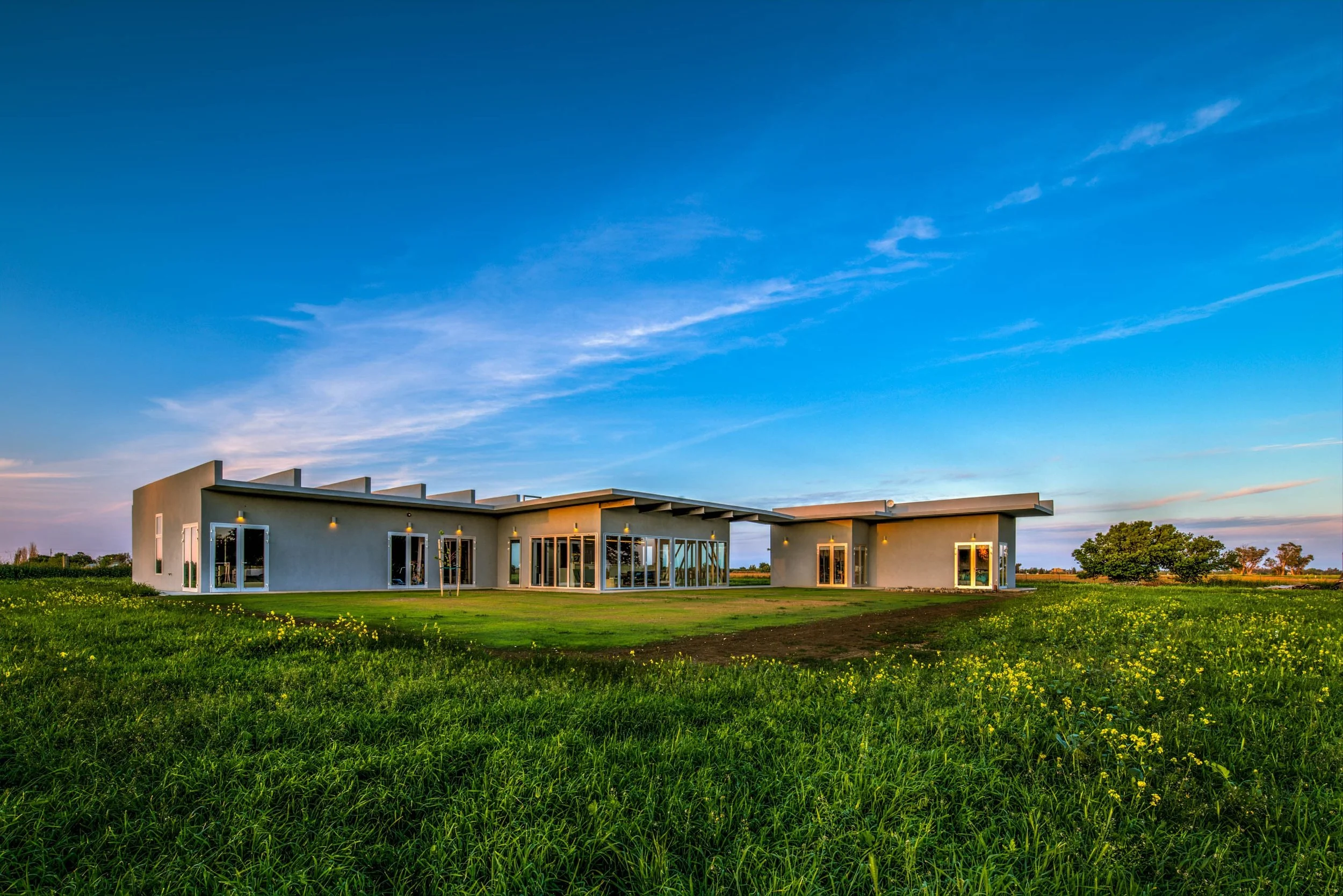 Four boxes—bedroom, living-dining-kitchen, work, and guest pods—form two structures arranged on an eight-foot grid. Separate live and work structures connect through a breezeway.