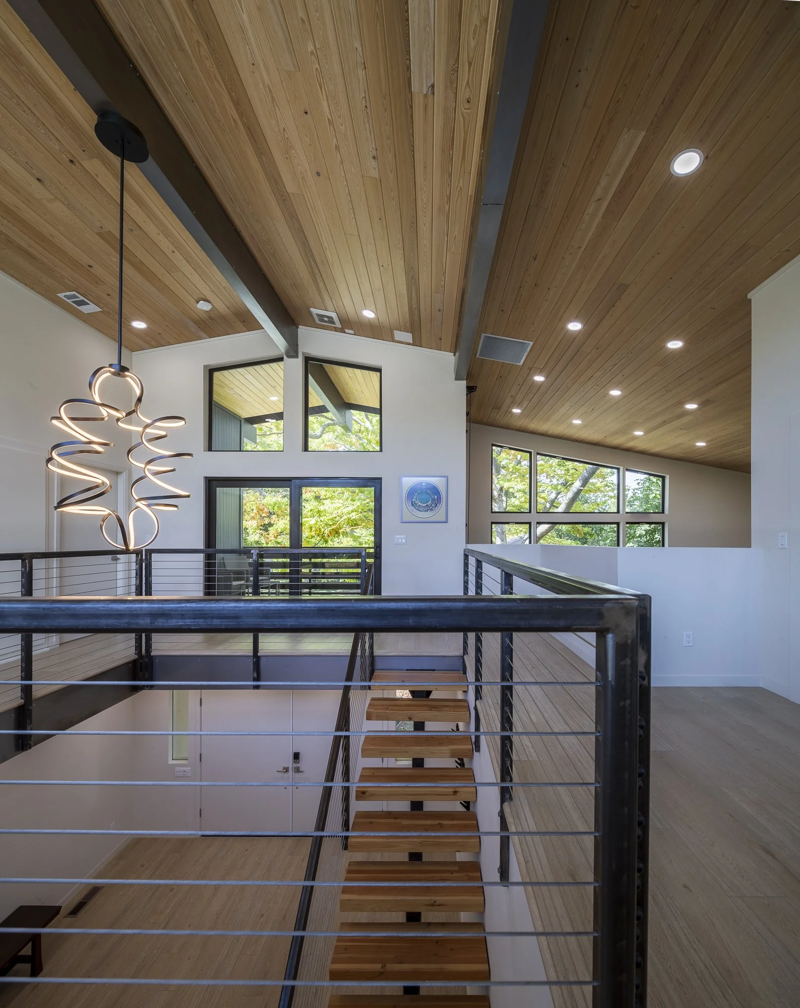 The upper level opens onto an elevated private deck and an interior double-height climbing wall in the open game room.