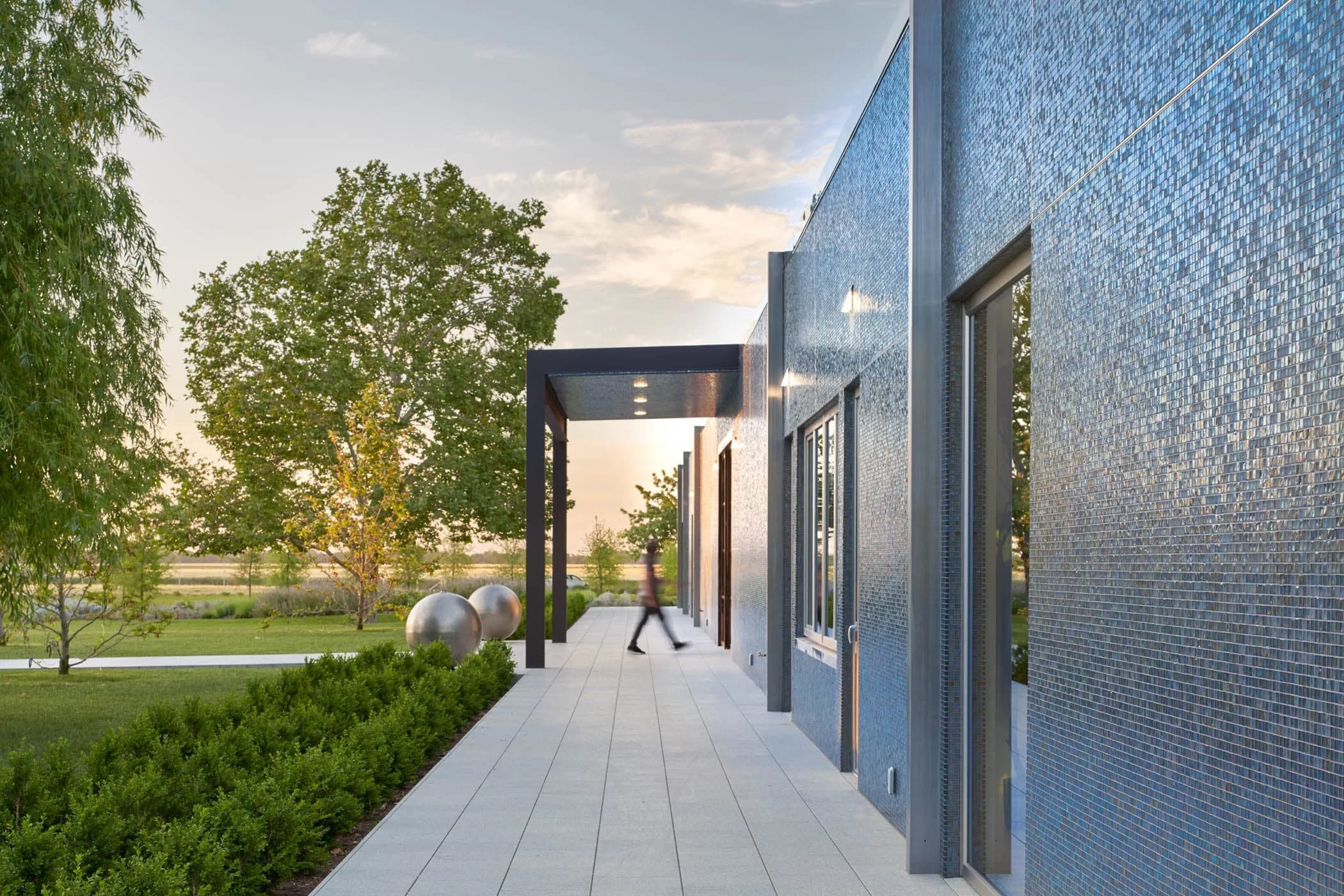 The exterior cladding, the first large installation of its kind, consists of one-inch glass tiles made by fusing silver nitrate onto glass in a superheated furnace. Delicate and ethereal, the result is a mosaic of depth and vitality—the house shimmer