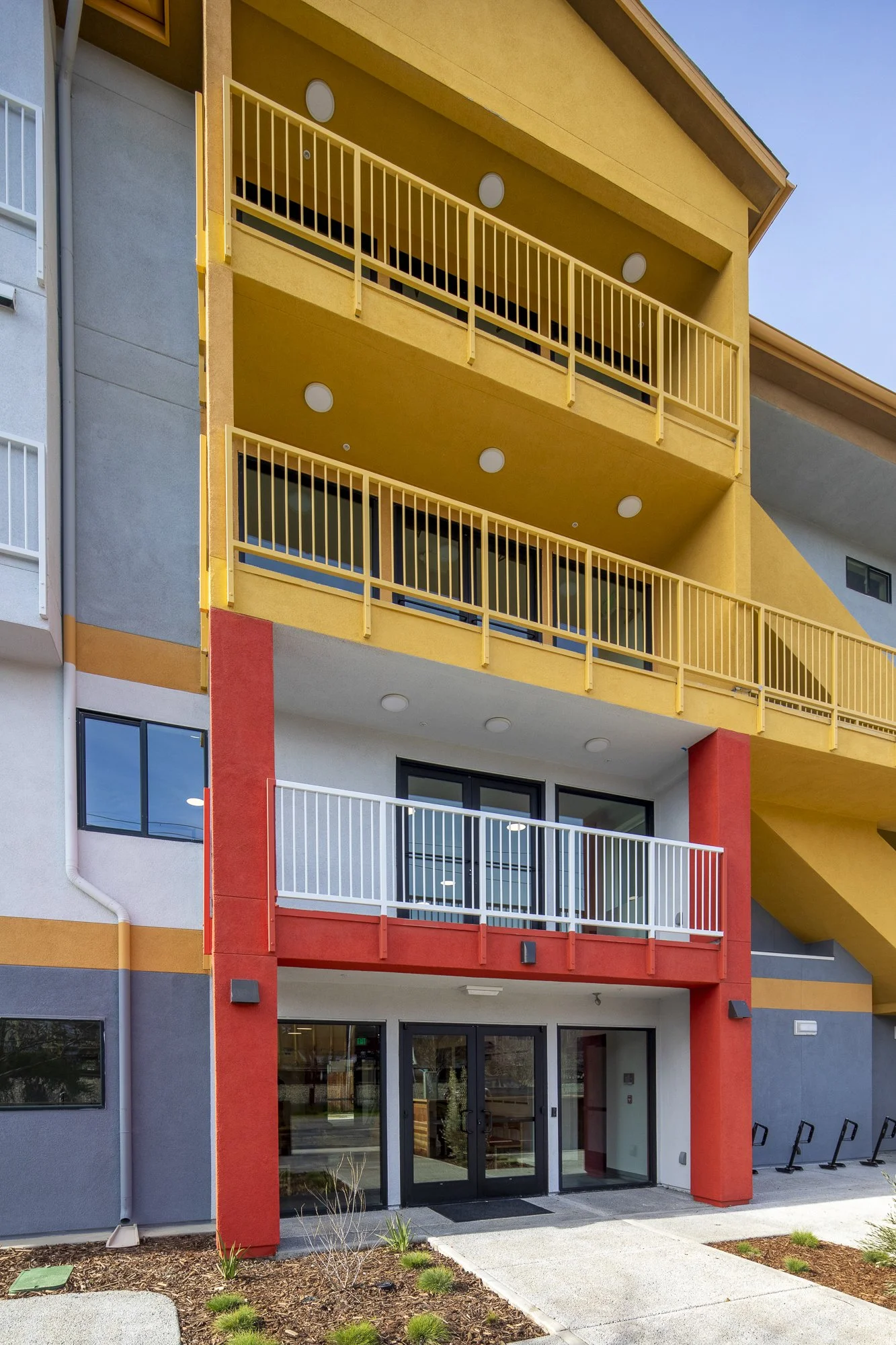 The ground floor offers day services like laundry, a kitchen, showers, and support staff and is marked with an oversized poppy-red 'H' at the main entrance.
