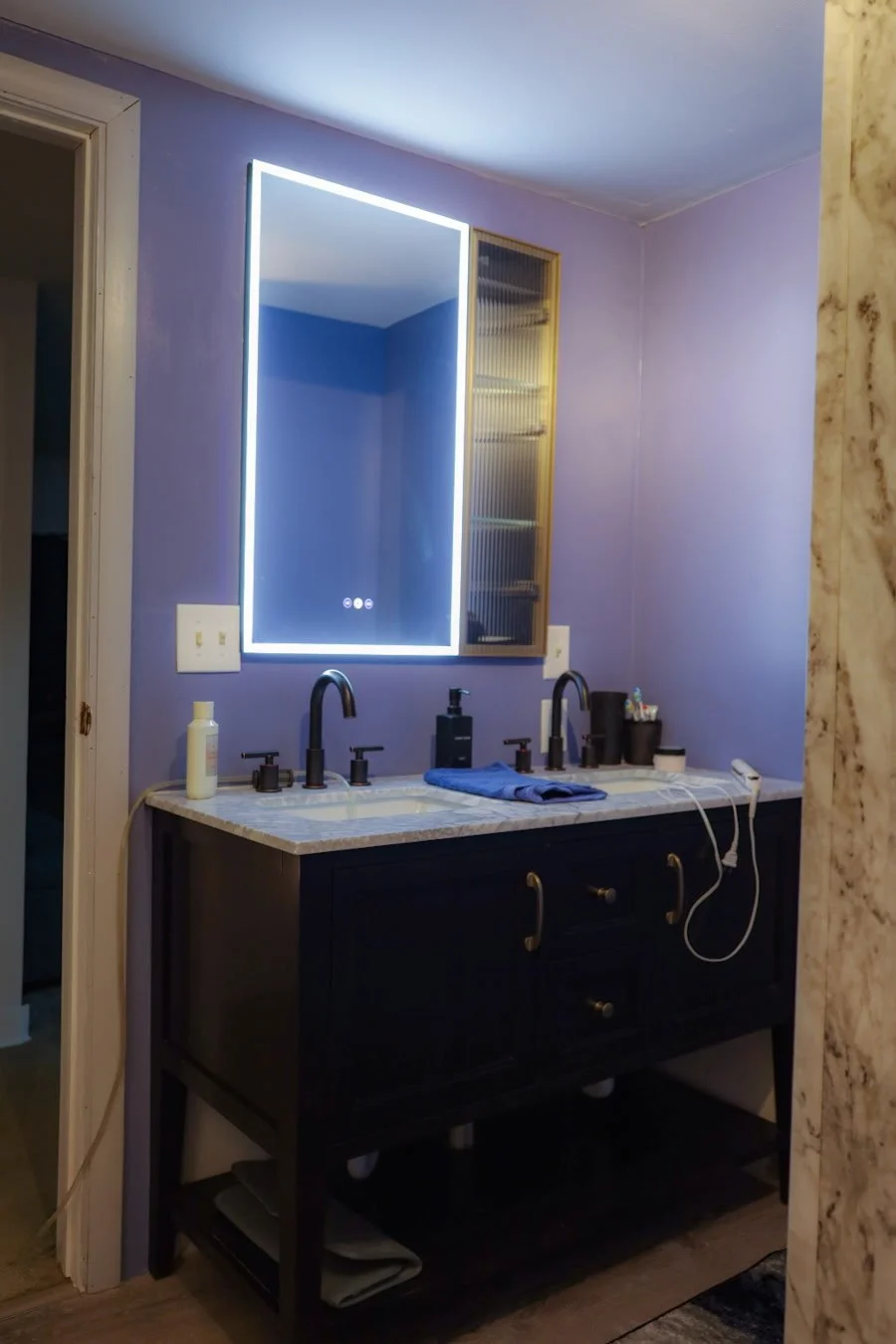 Bathroom sink with mirror hung from the wall, blue towel folded between twin sinks, blue walls freshly painted