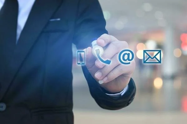 Zakelijke man in zwart pak tikt op een digitale interface met iconen voor telefoon, e-mail, @ en berichten.