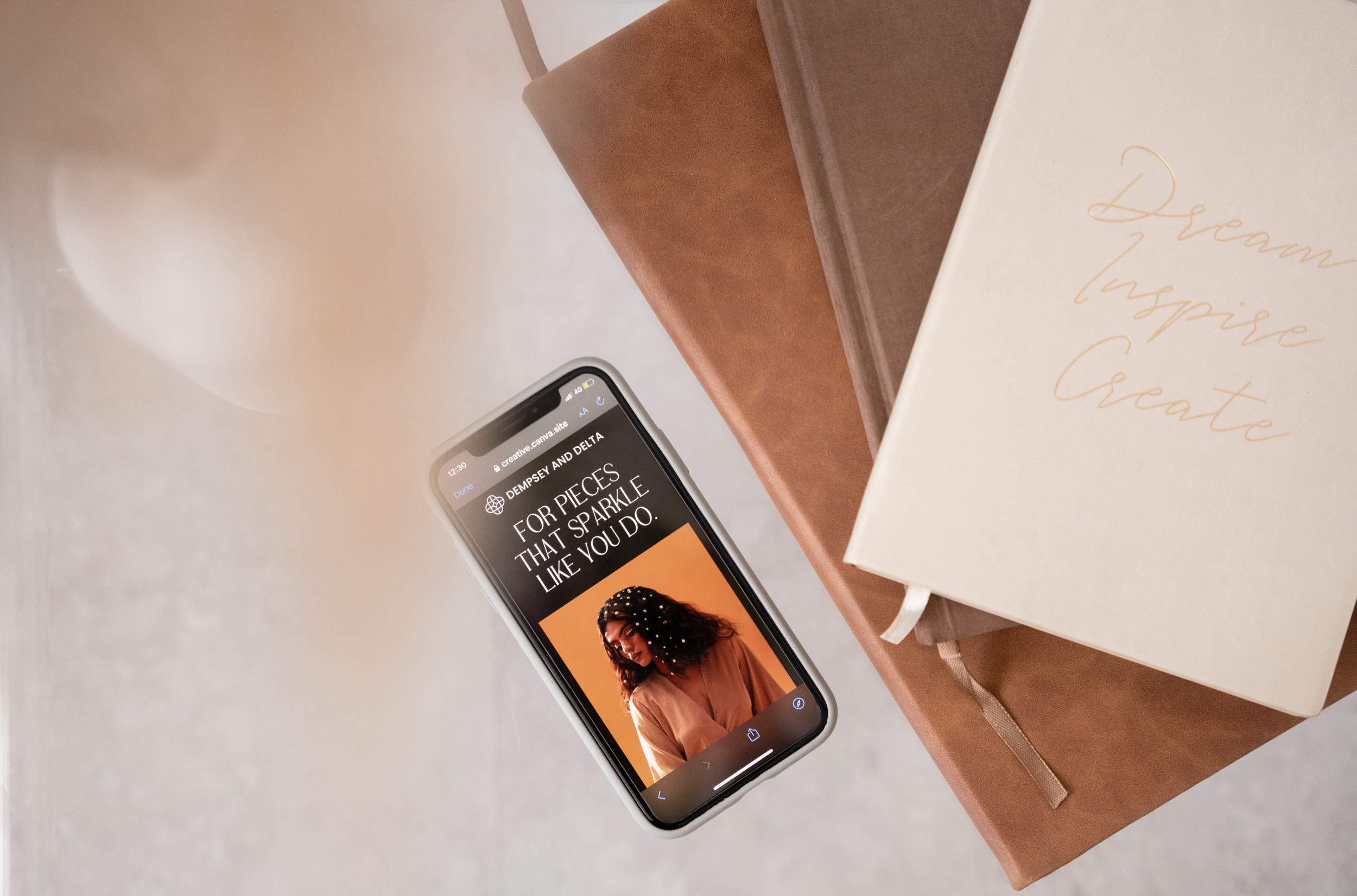 A smartphone displaying a fashion website next to three journals on a table.