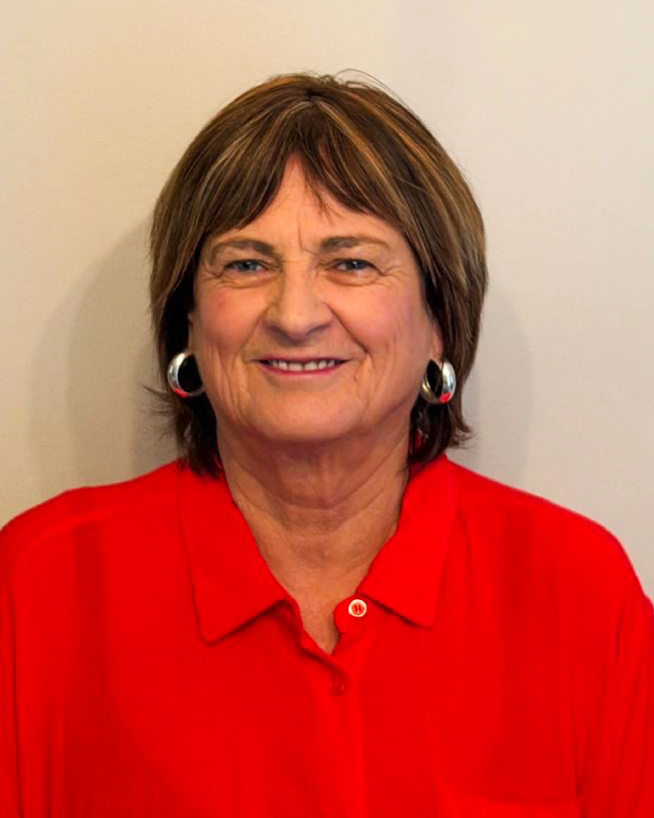Charmaine Stemmet, accounts manager at Supragas. Close-up of a smiling woman with short brown hair wearing a red collared shirt and large hoop earrings, standing against a plain light-colored wall.
