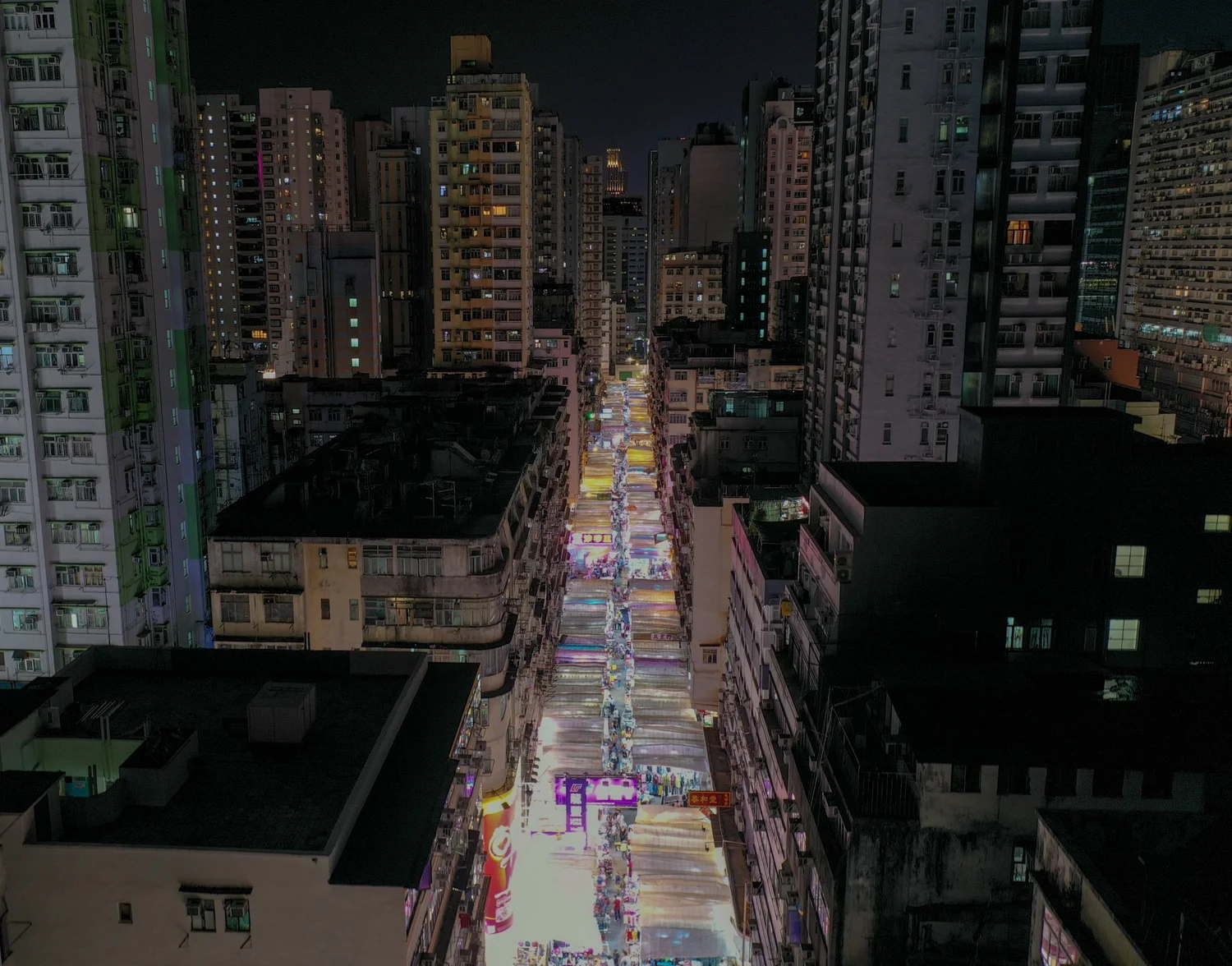 Drone view down a narrow street between tall buildings in Hong Kong