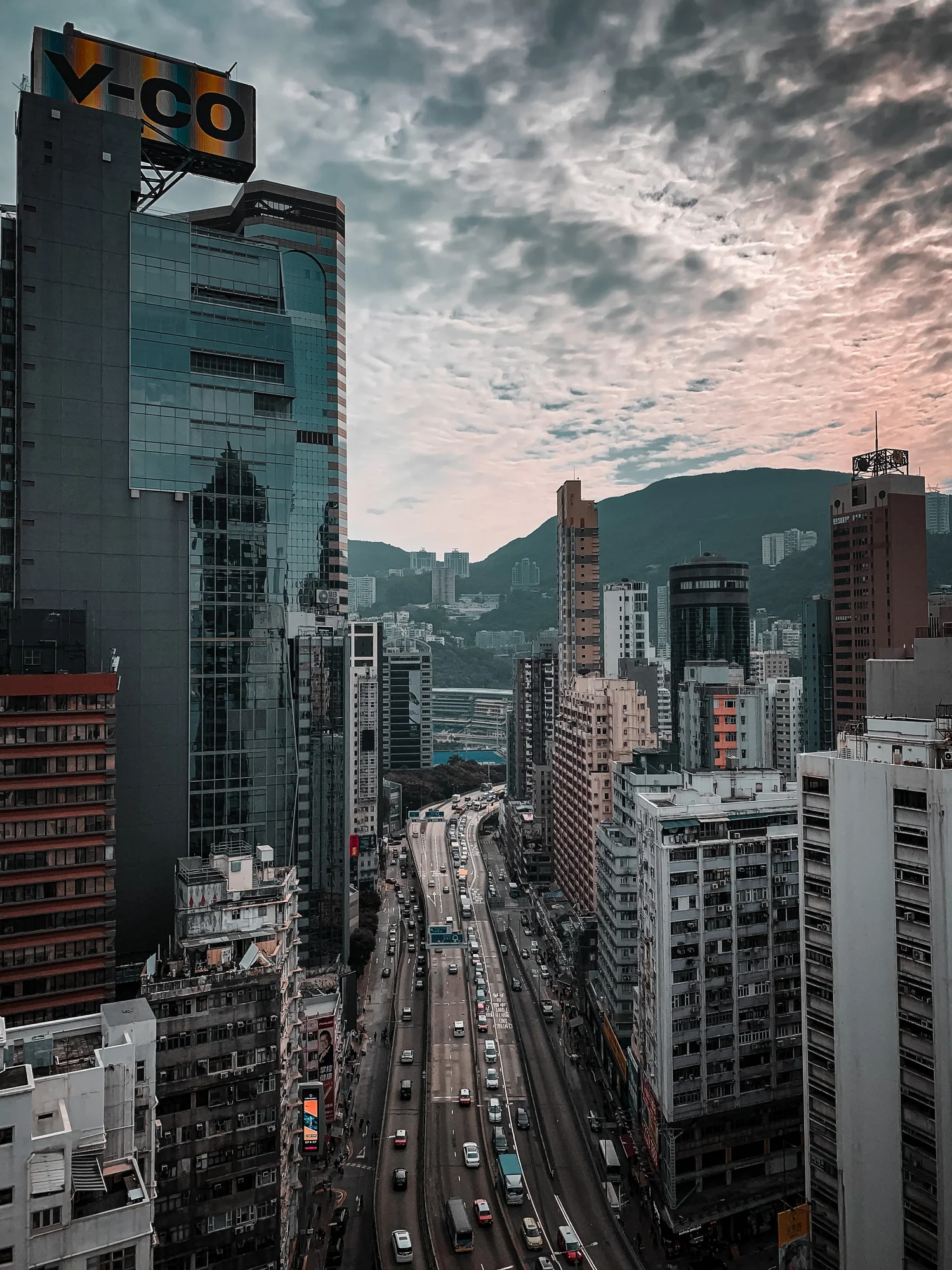 Hong Kong street lined with tall buildings under a cloudy sky
