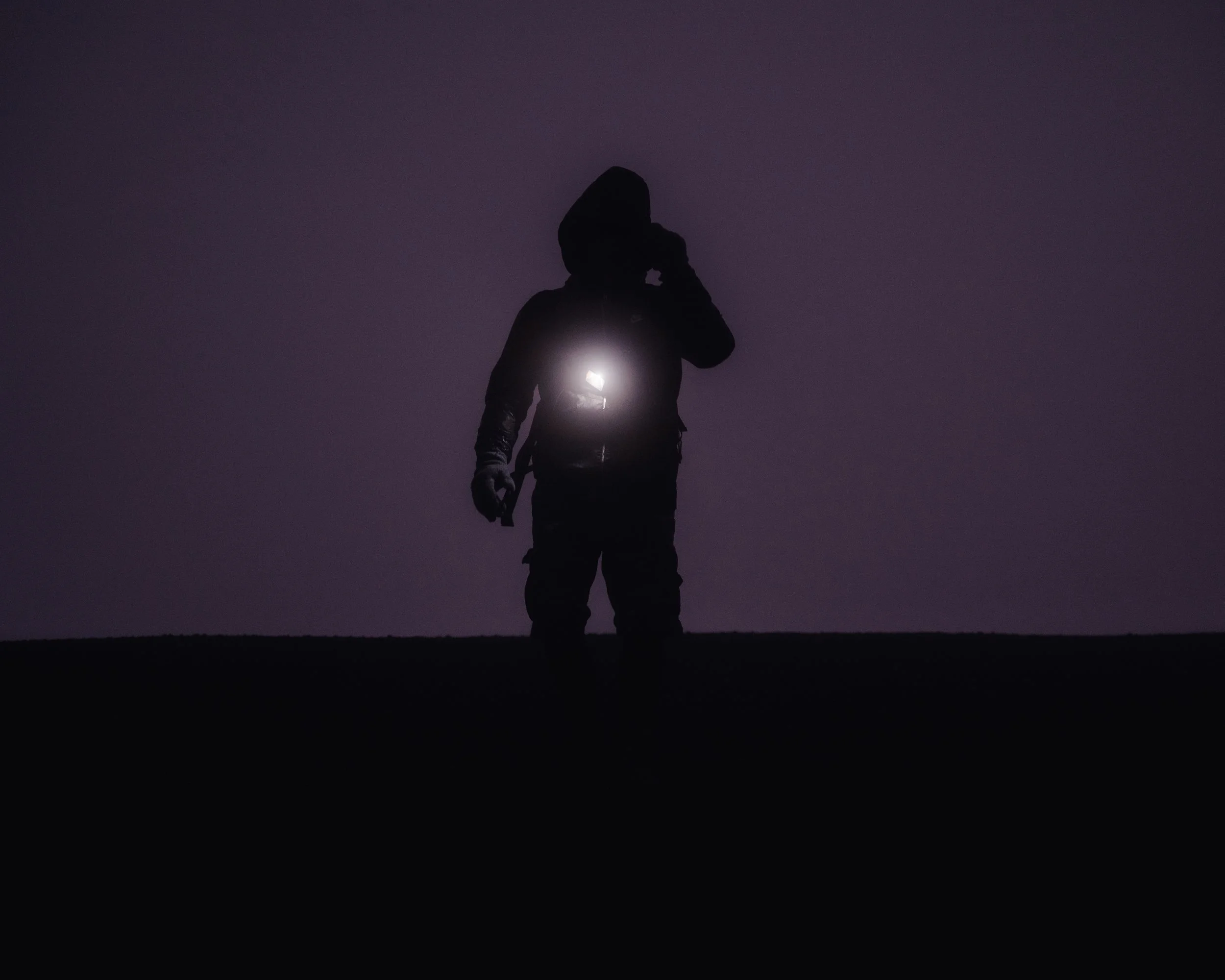 Silhouette d'une personne tenant une torche allumée dans un environnement sombre.