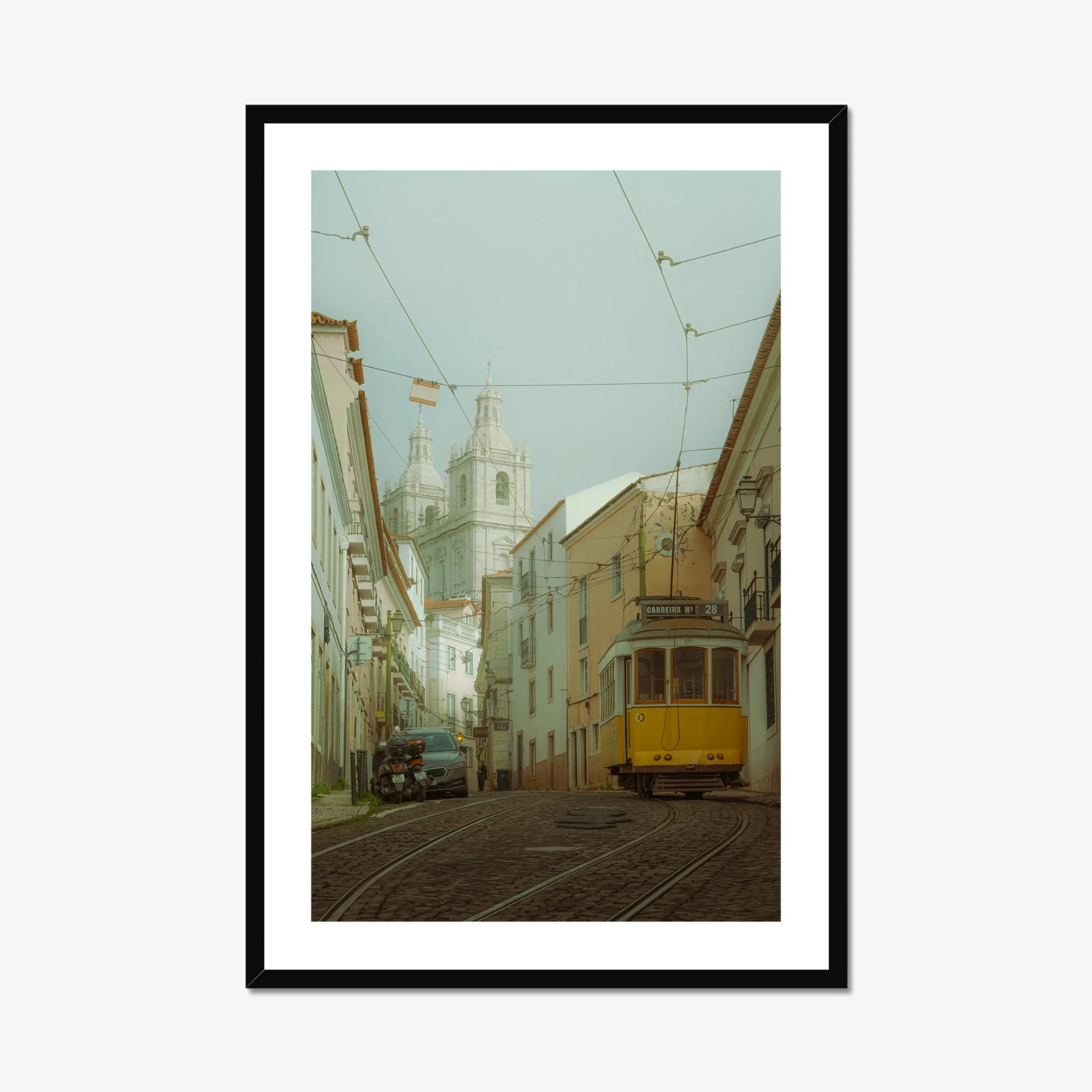 ejduranphotography Fine Art Lisbon print. Cinematic street photography of the iconic yellow Tram 28 on a winding cobblestone street with a misty church background. Moody wall art decor.