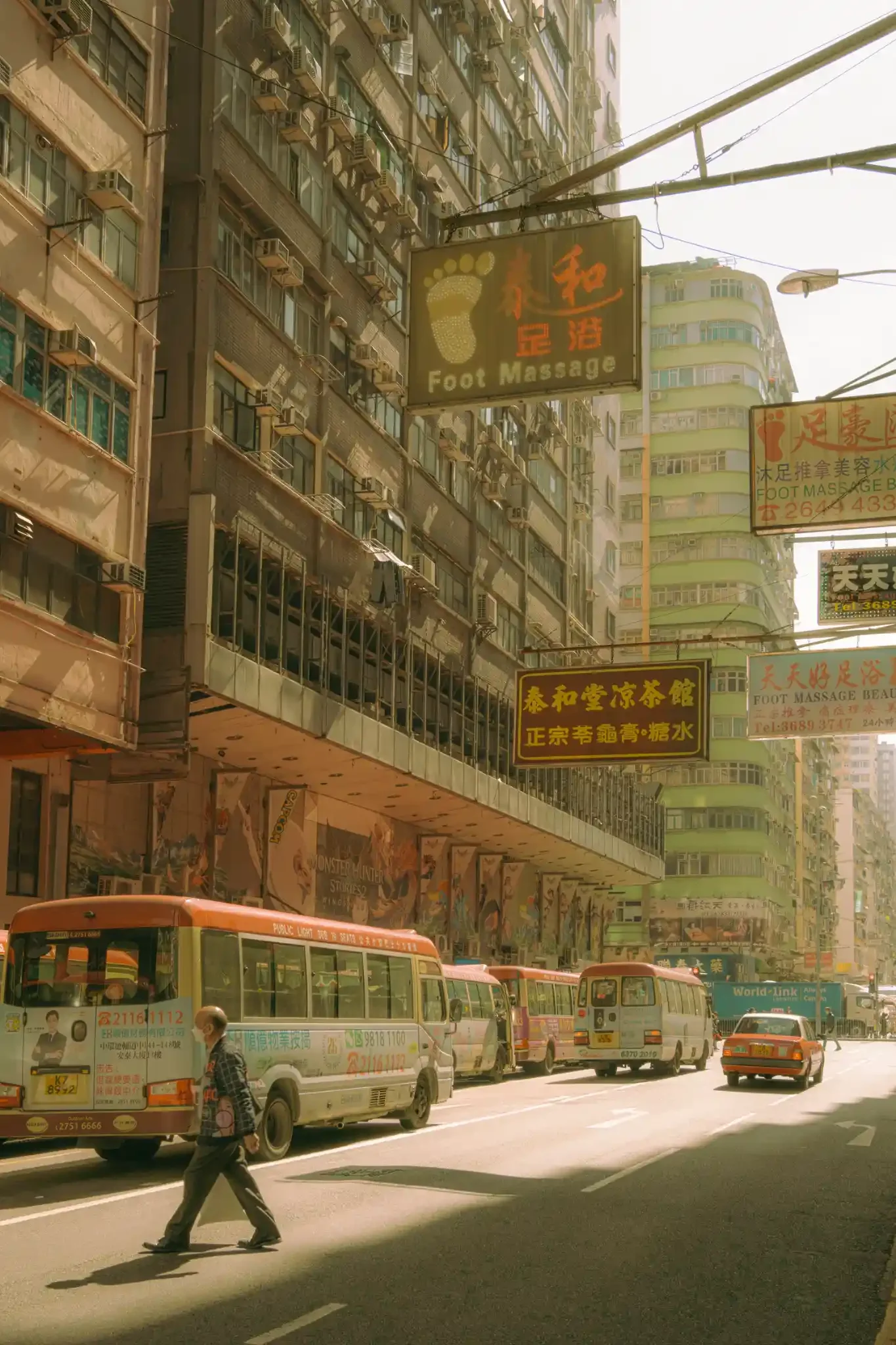 Sun-drenched Hong Kong street photography fine art print. Cinematic urban scene with red-topped minibuses, a red taxi, vintage signs, and a pedestrian crossing. Warm amber wall art decor.