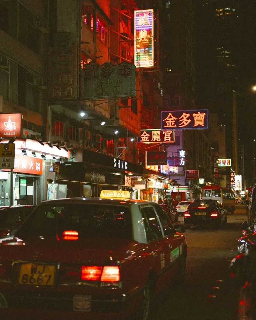 Before and after comparison using Lomography 800 Lightroom preset on a night street photography scene with vibrant neon lights and film grain.