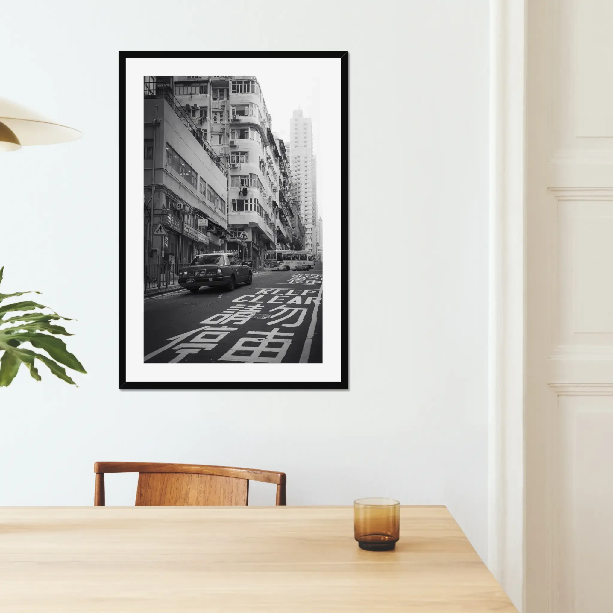 Black and white street photography print of a classic Hong Kong taxi driving up a steep hill towards a minibus. Features high-contrast shadows and strong urban geometry. Fine art wall decor