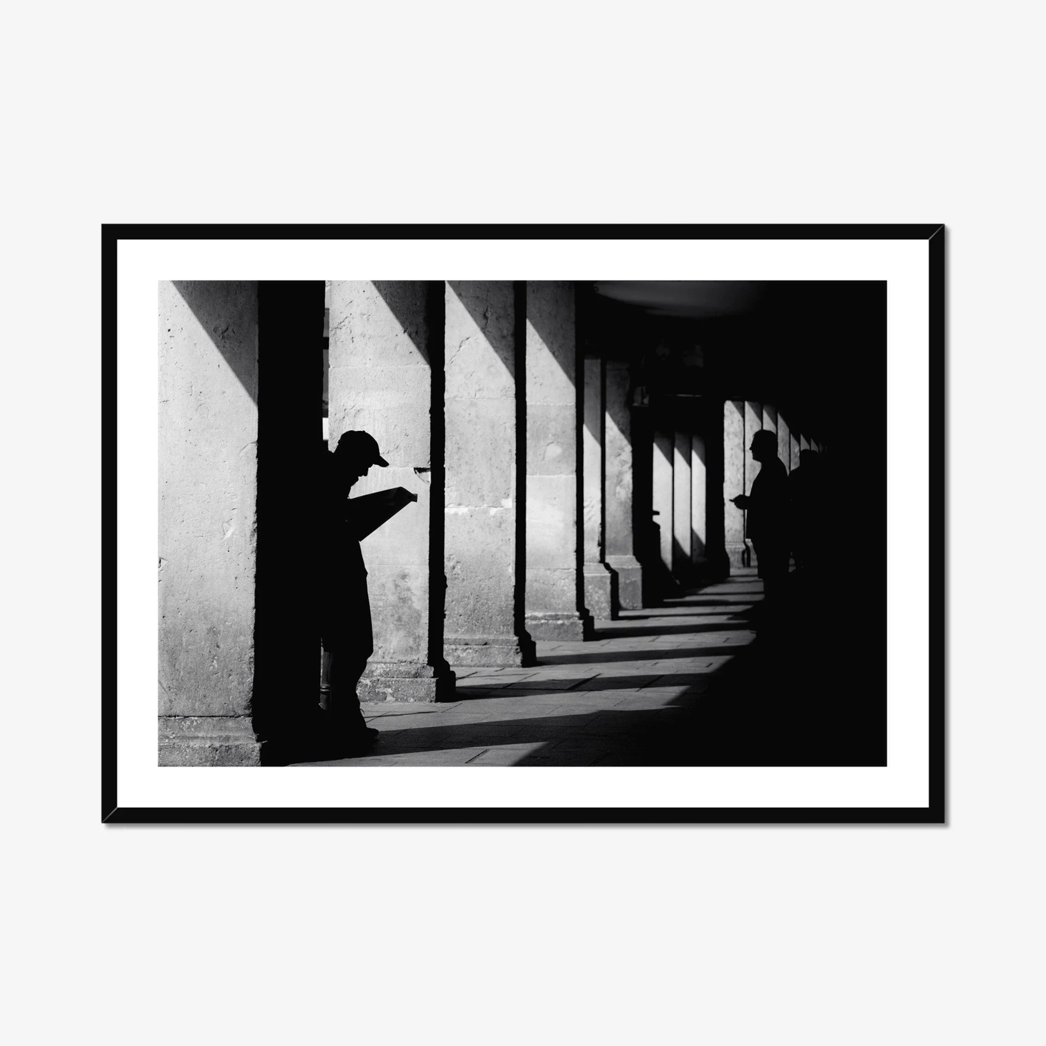 Black and white minimalist street photography print of a lone figure walking up an outdoor staircase. Features strong geometric lines and high-contrast dramatic shadows. Fine art wall decor.
