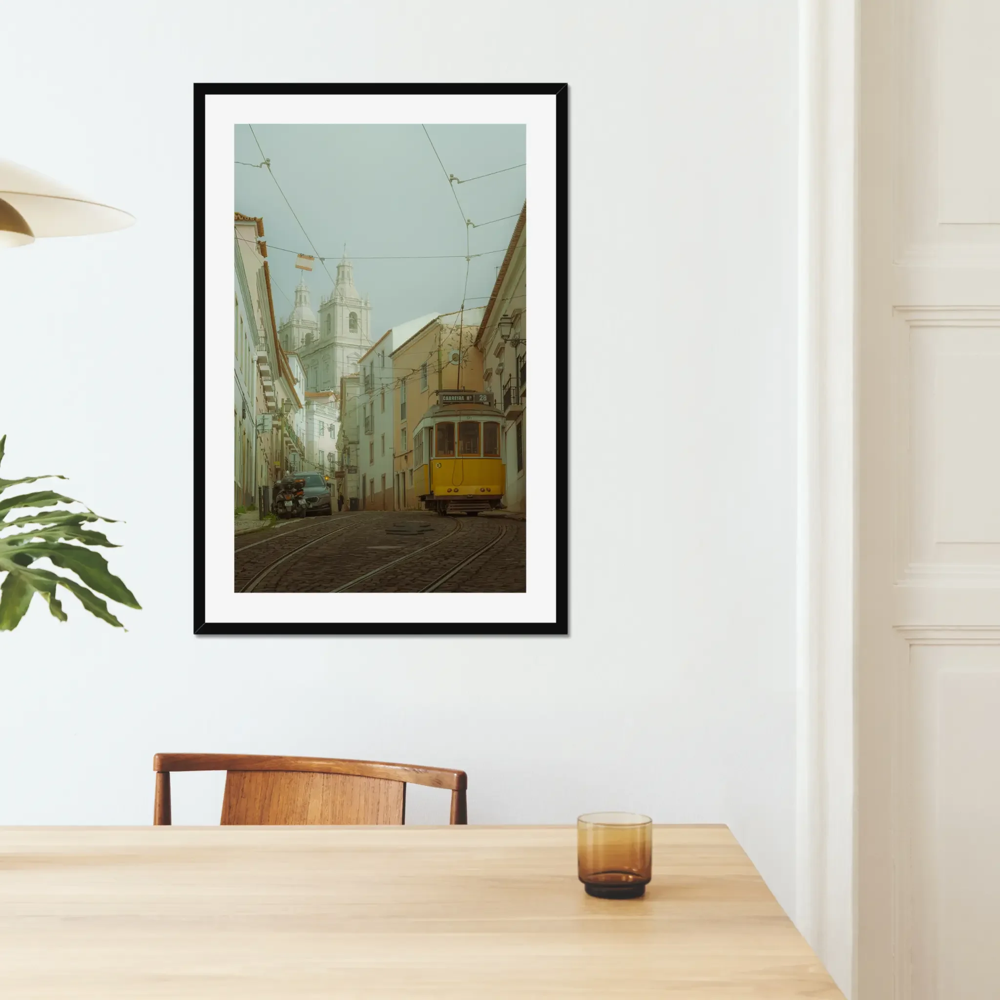ejduranphotography Fine Art Lisbon print. Cinematic street photography of the iconic yellow Tram 28 on a winding cobblestone street with a misty church background. Moody wall art decor.