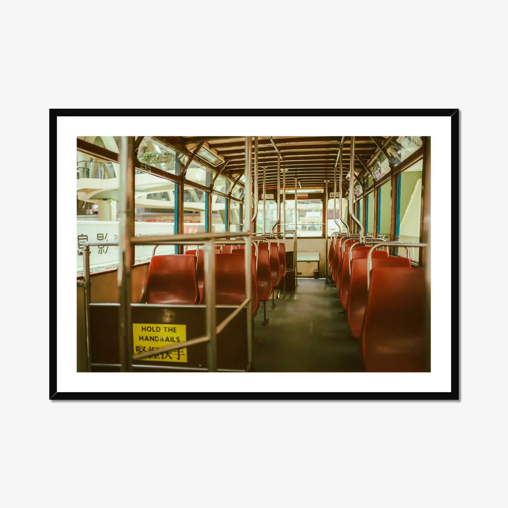 Vintage Hong Kong tram interior fine art print featuring red seats and a hold the handrails sign in warm cinematic tones.