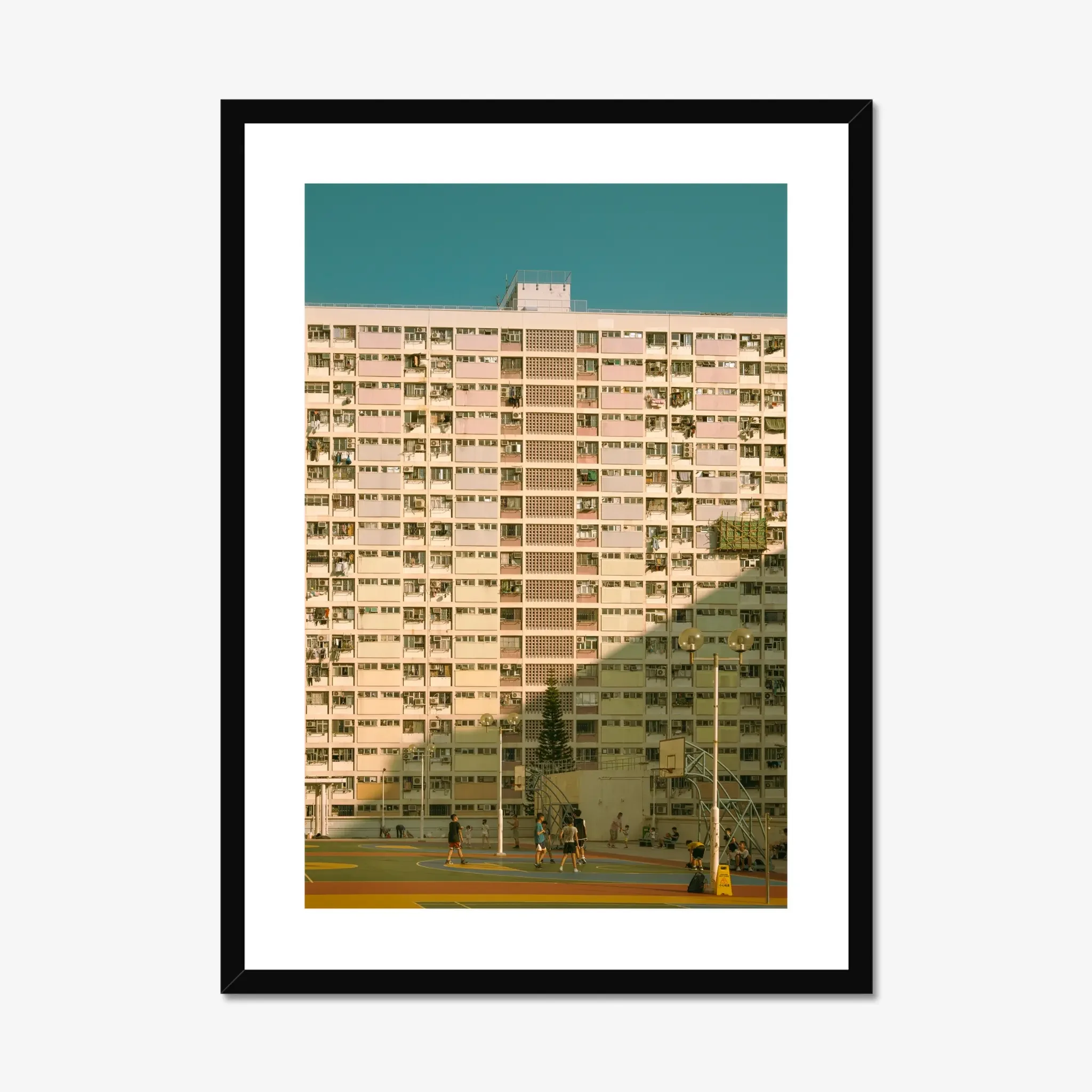 Vintage pastel building of Choi Hung Estate in Hong Kong with a colorful basketball court at golden hour.