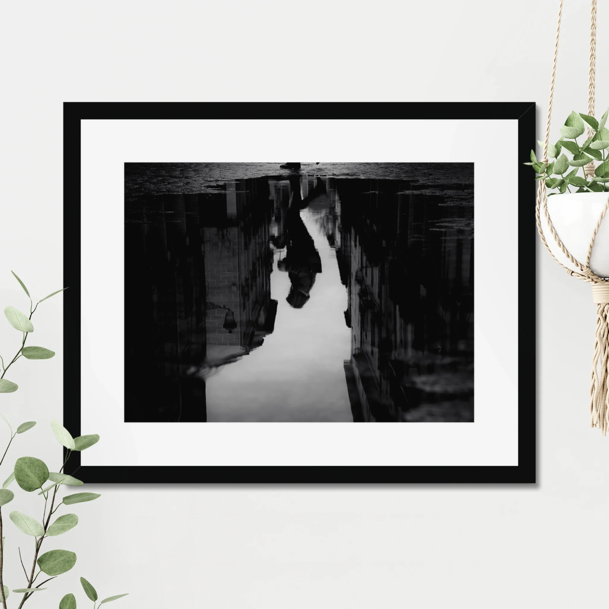 Black and white moody street photography print of a person with an umbrella walking in the rain. Features a striking reflection on wet pavement. Cinematic fine art wall decor.