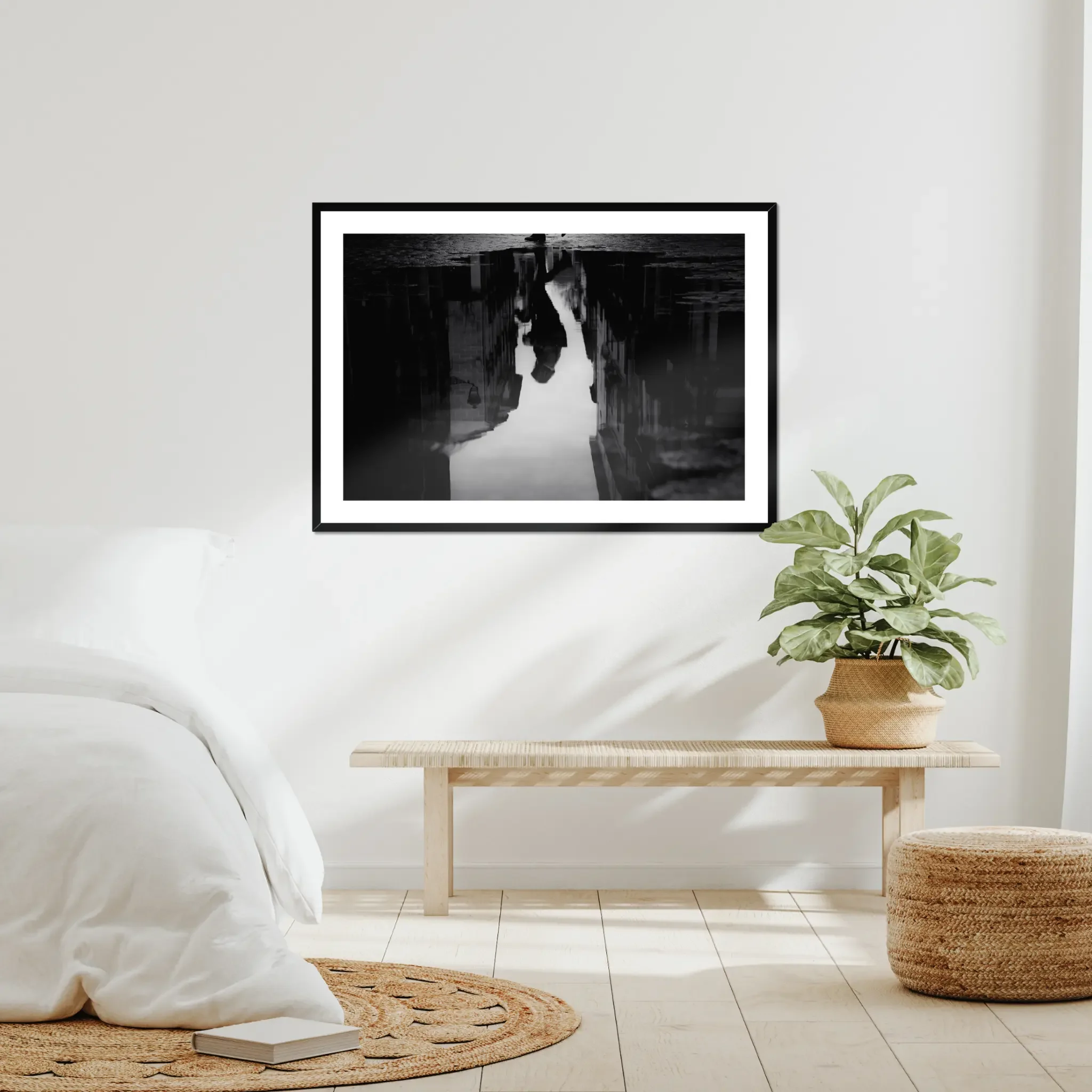 Black and white moody street photography print of a person with an umbrella walking in the rain. Features a striking reflection on wet pavement. Cinematic fine art wall decor.