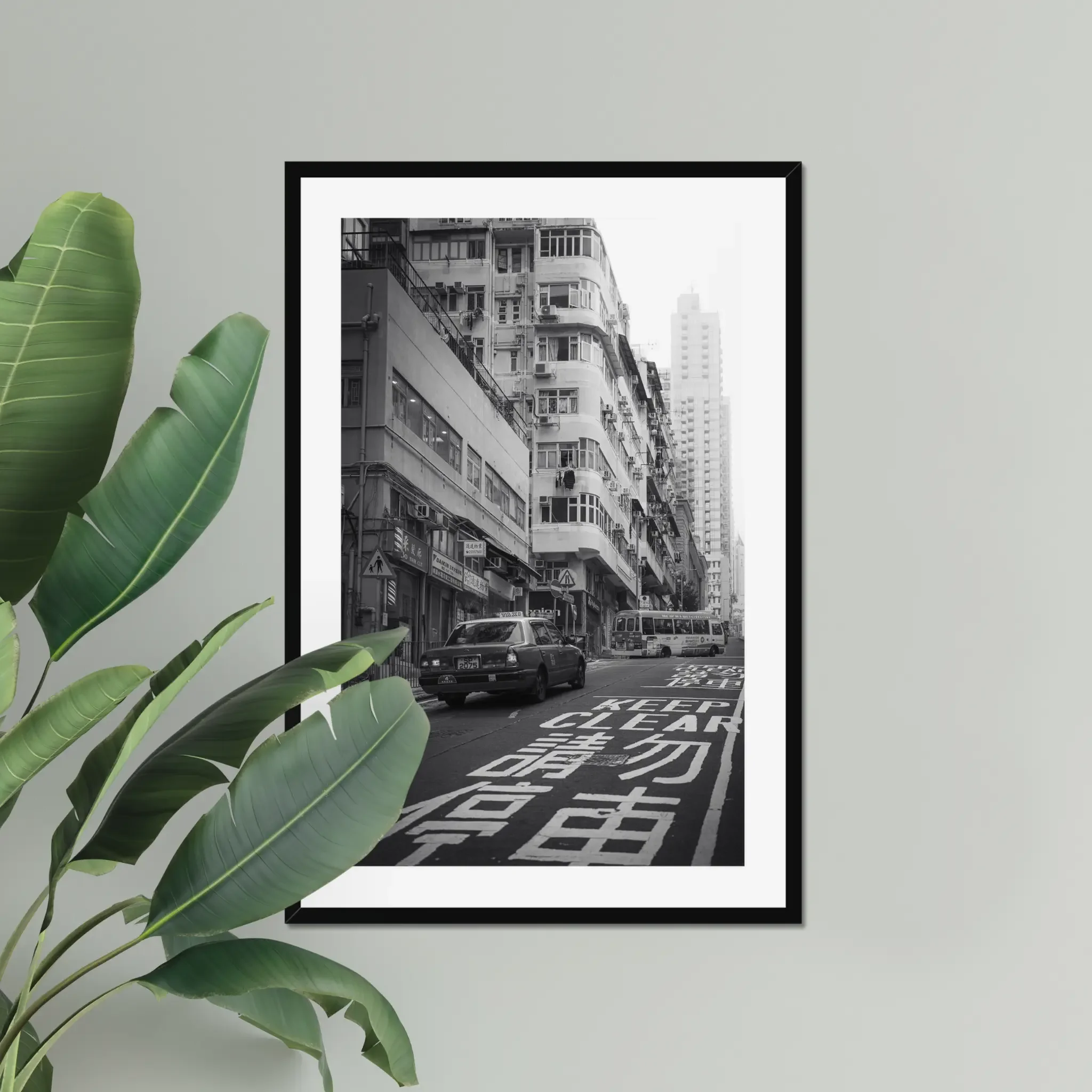 Black and white street photography print of a classic Hong Kong taxi driving up a steep hill towards a minibus. Features high-contrast shadows and strong urban geometry. Fine art wall decor