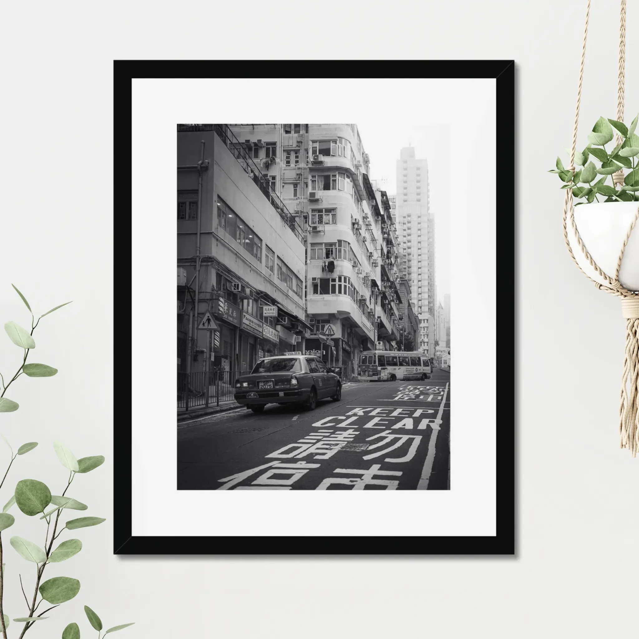 Black and white street photography print of a classic Hong Kong taxi driving up a steep hill towards a minibus. Features high-contrast shadows and strong urban geometry. Fine art wall decor