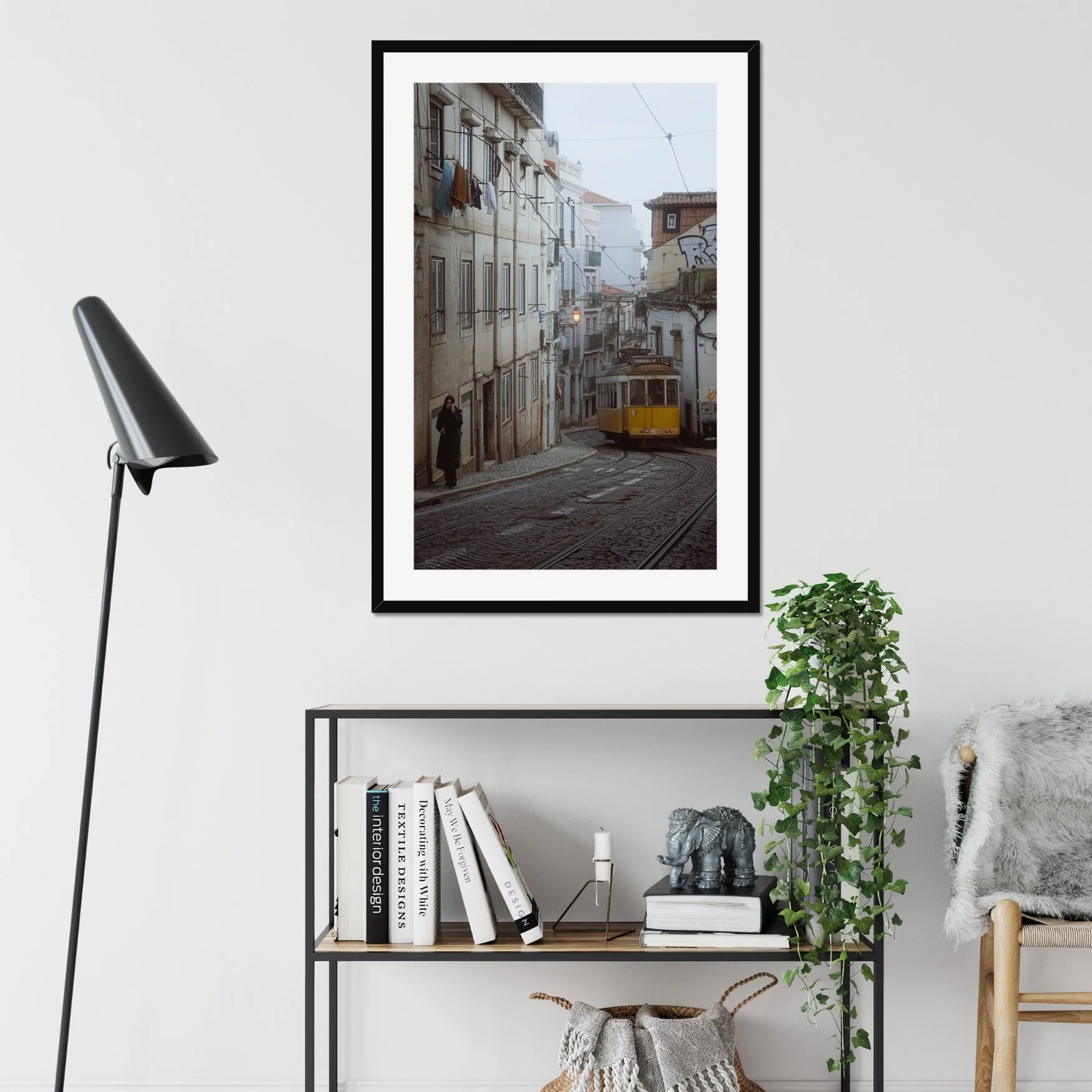 Black and white or muted tone photography of a Lisbon tram in Alfama street, winding cobblestone road with a person walking, minimalist Portuguese urban wall art.