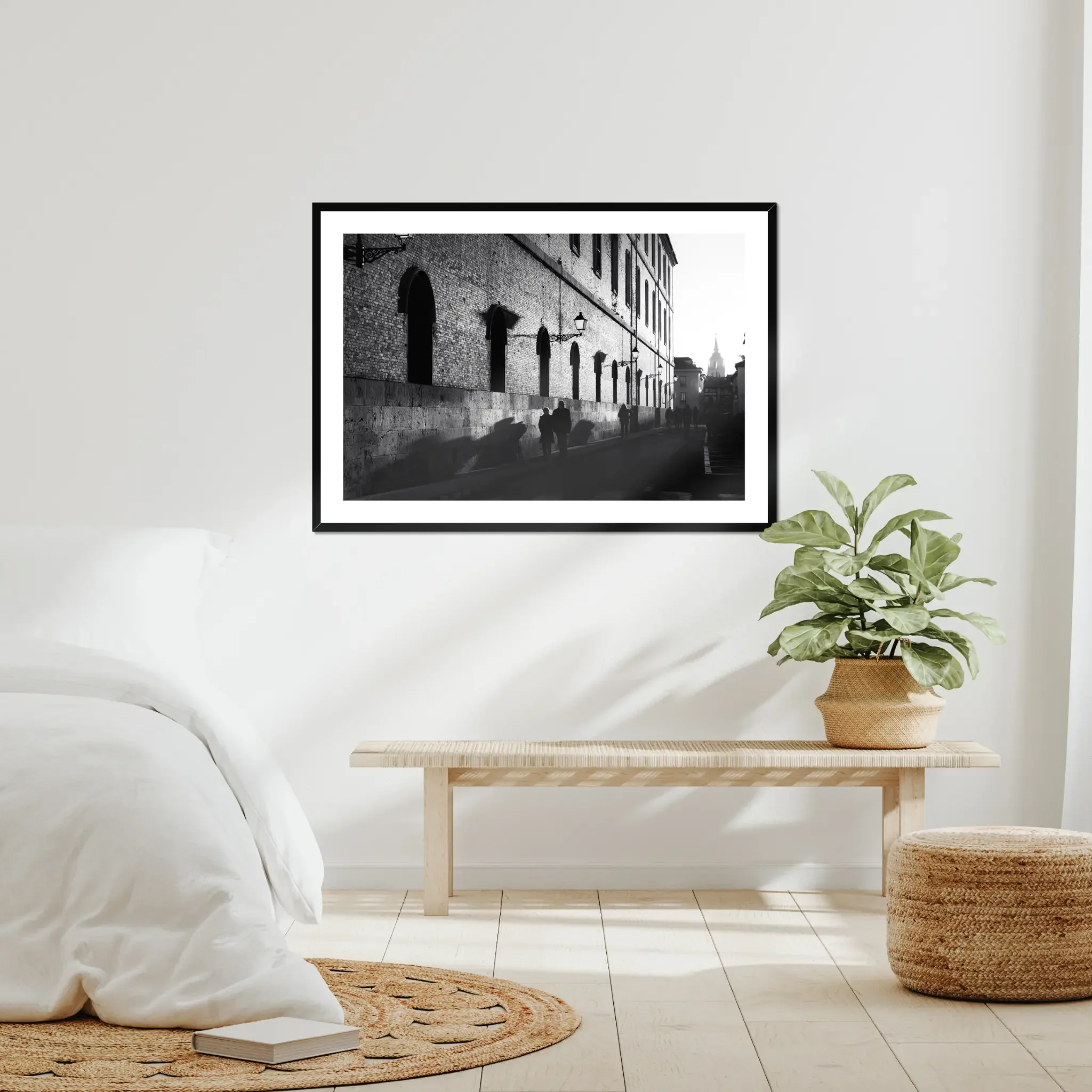 Black and white street photography print of a person walking past a textured historical wall. Features striking diagonal shadows and high-contrast lighting. Classic fine art monochrome decor.