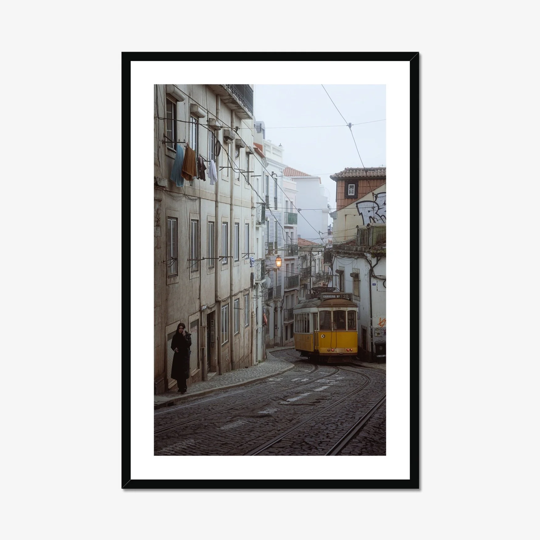 Black and white or muted tone photography of a Lisbon tram in Alfama street, winding cobblestone road with a person walking, minimalist Portuguese urban wall art.