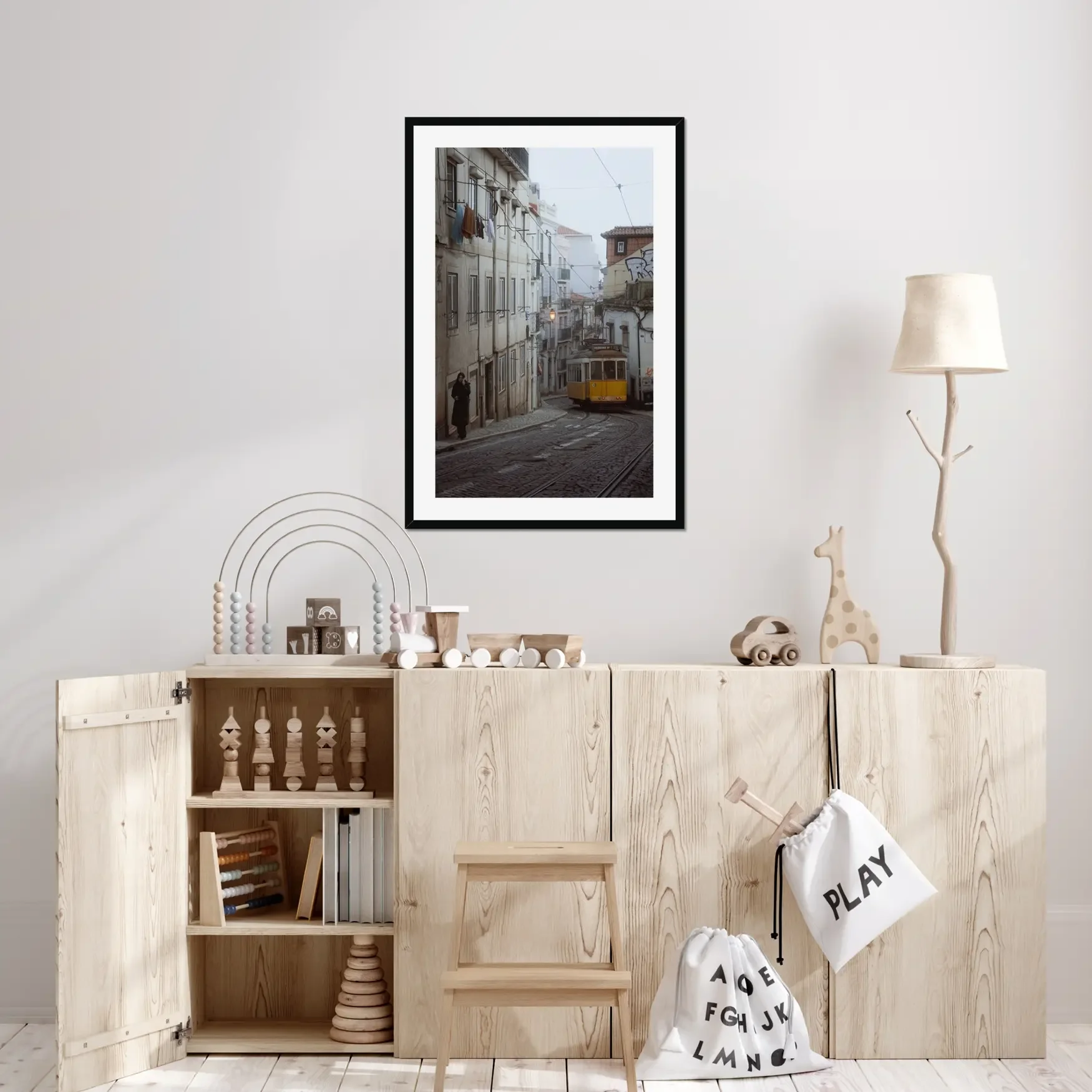 Black and white or muted tone photography of a Lisbon tram in Alfama street, winding cobblestone road with a person walking, minimalist Portuguese urban wall art.