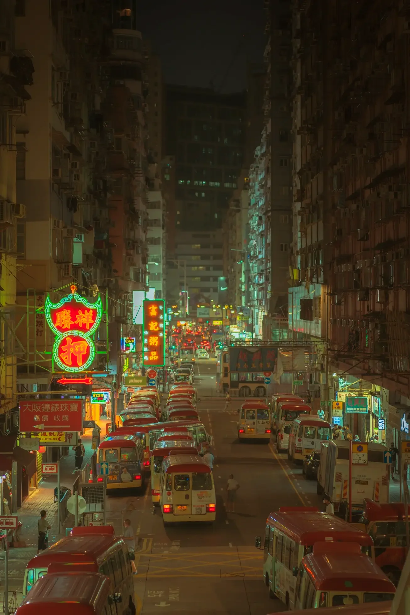 Elevated view of Hong Kong red minibuses queued on a Mong Kok street at night, with green neon shop signage