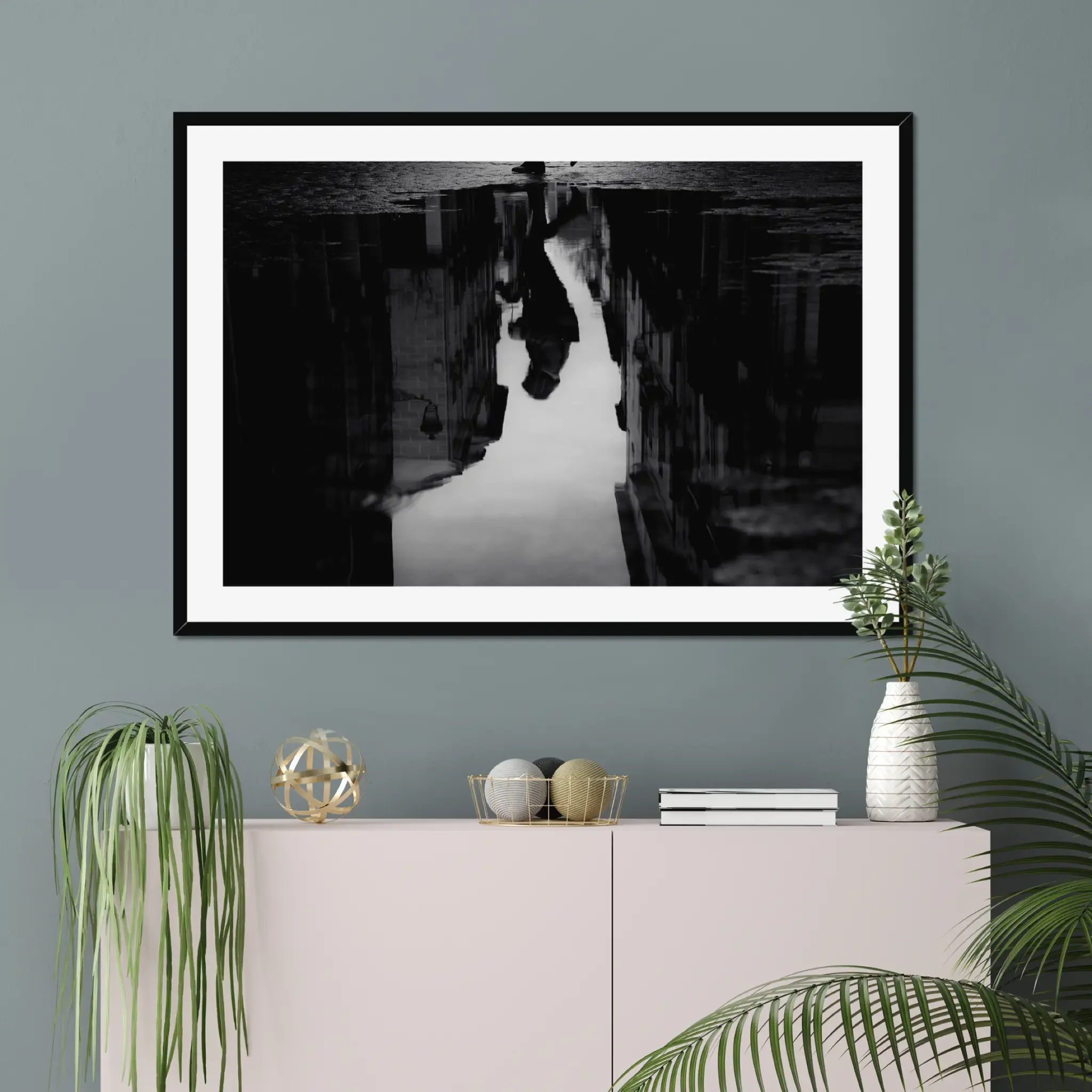 Black and white moody street photography print of a person with an umbrella walking in the rain. Features a striking reflection on wet pavement. Cinematic fine art wall decor.