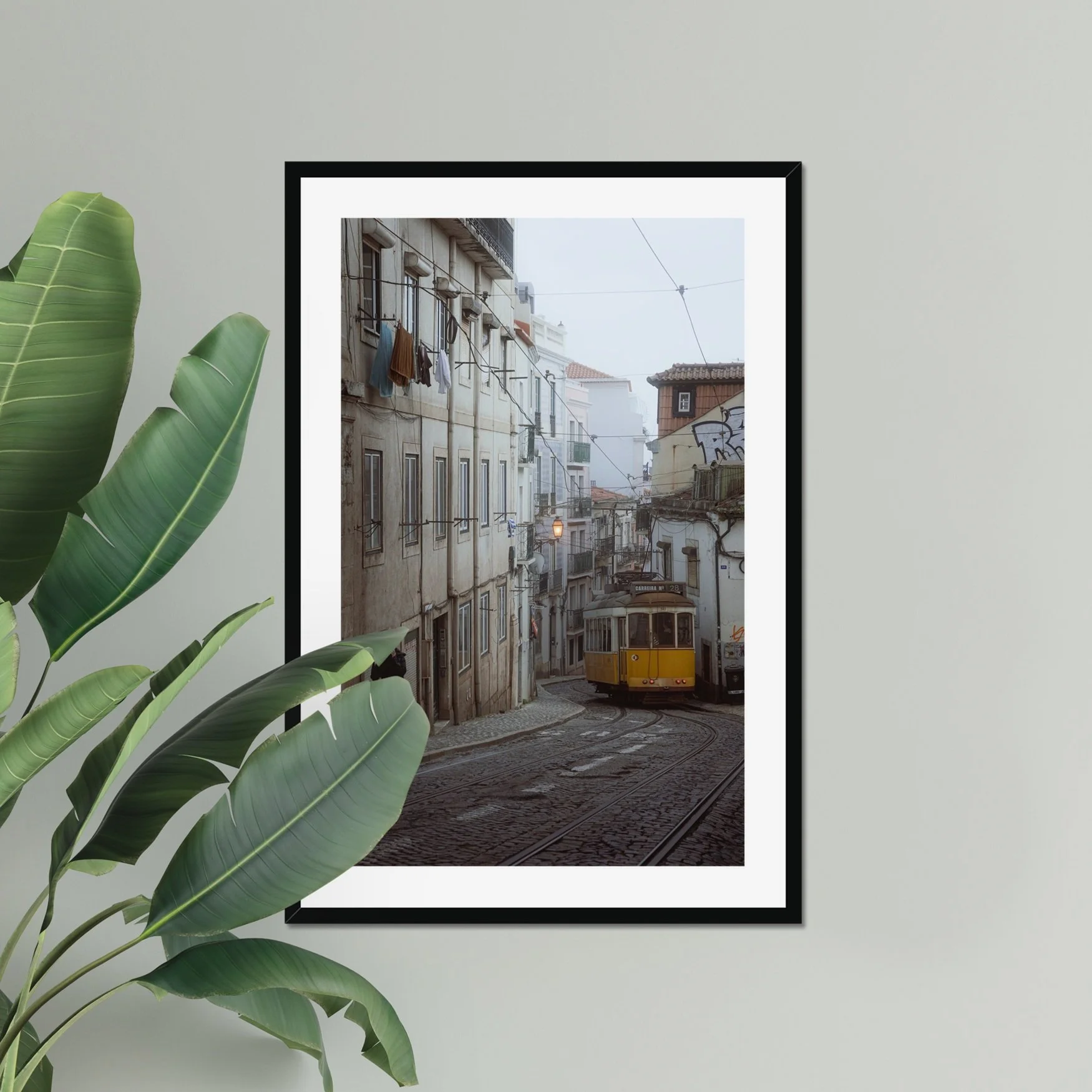 Black and white or muted tone photography of a Lisbon tram in Alfama street, winding cobblestone road with a person walking, minimalist Portuguese urban wall art.