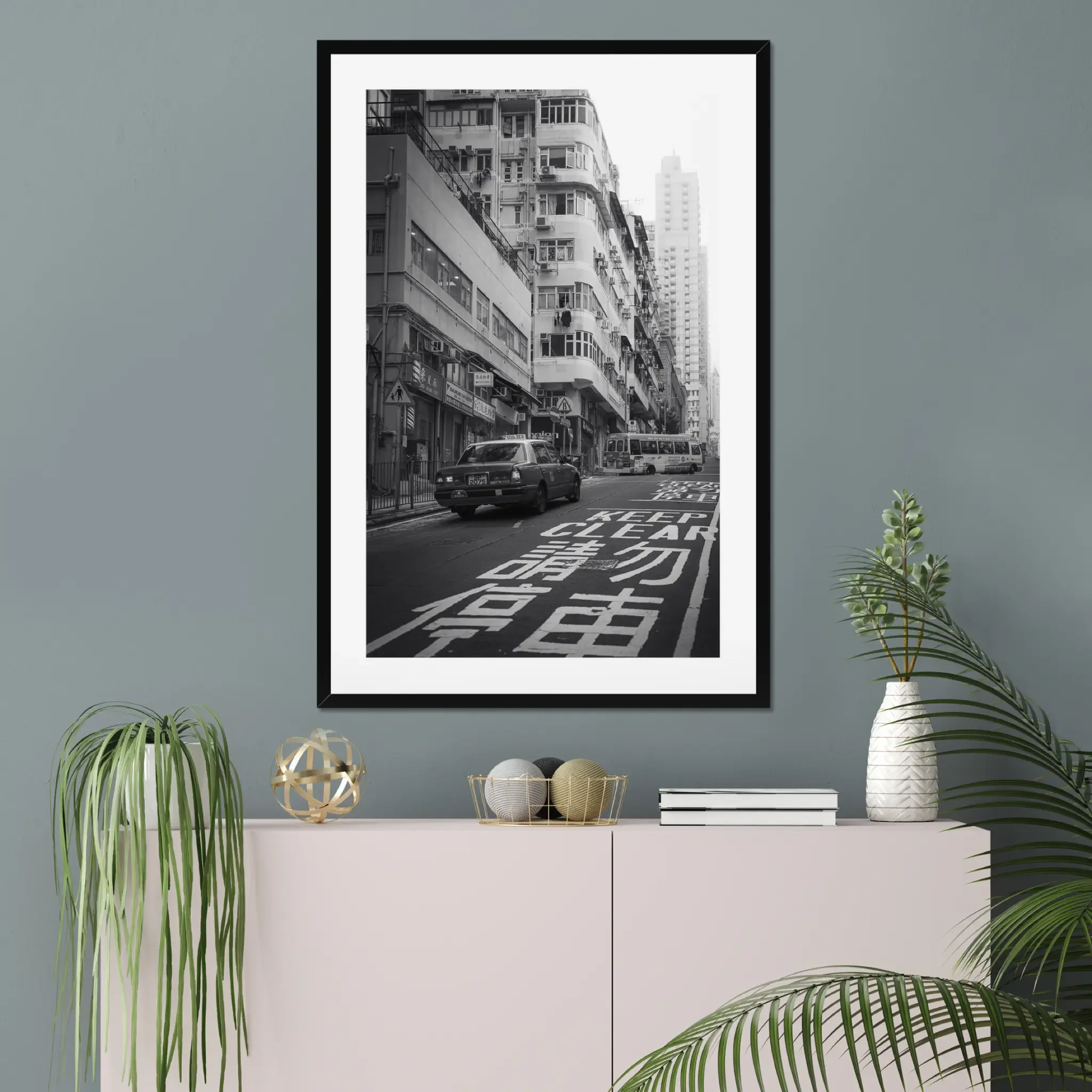 Black and white street photography print of a classic Hong Kong taxi driving up a steep hill towards a minibus. Features high-contrast shadows and strong urban geometry. Fine art wall decor