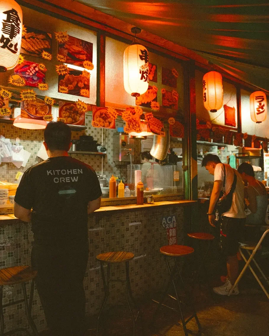 Before and after comparison using Lomography 800 Lightroom preset on a night street photography scene with vibrant neon lights and film grain.