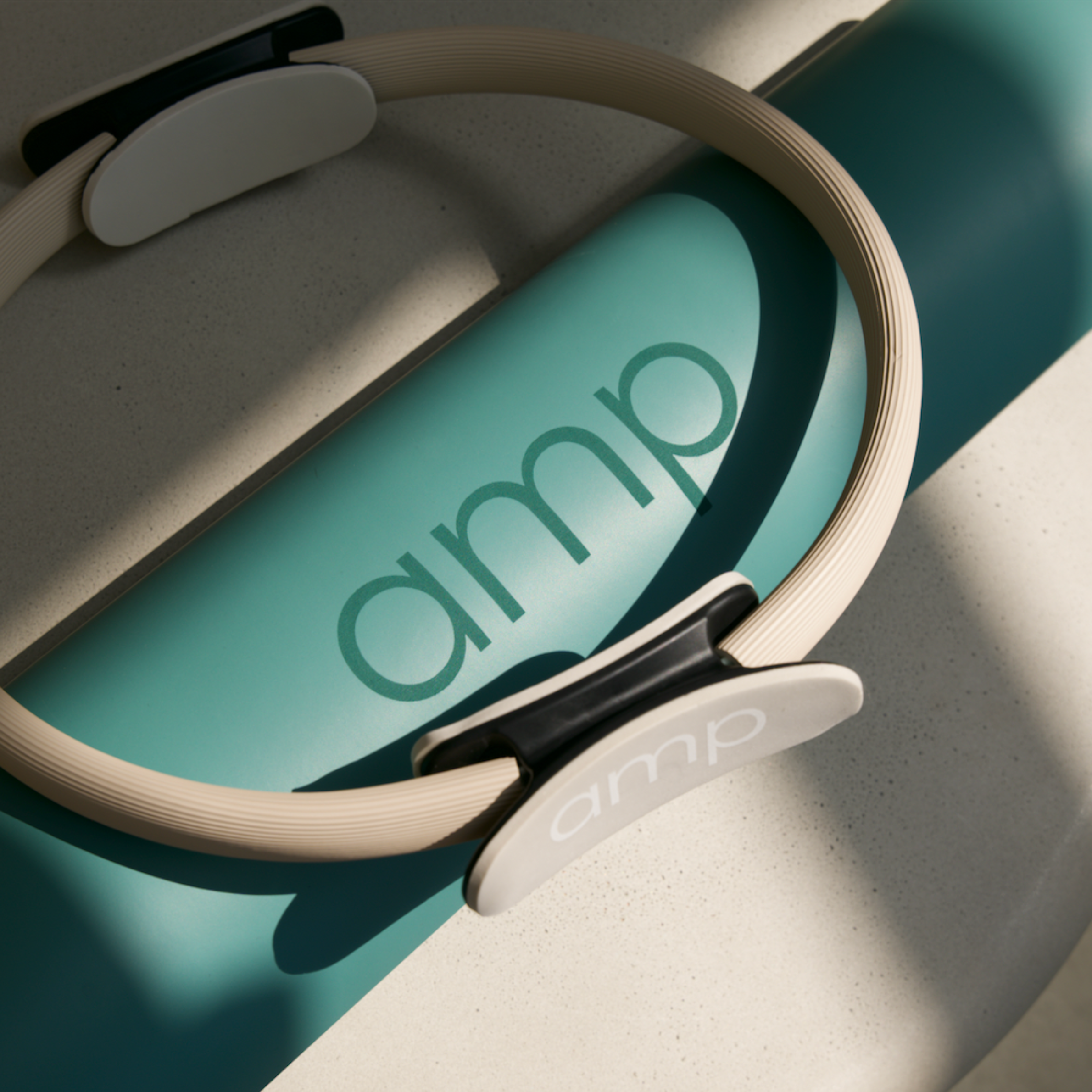 Close-up of a beige-colored circular object with black accents and a white bar, placed on a gray speckled surface, with part of a teal-colored board with text on it visible in the background.