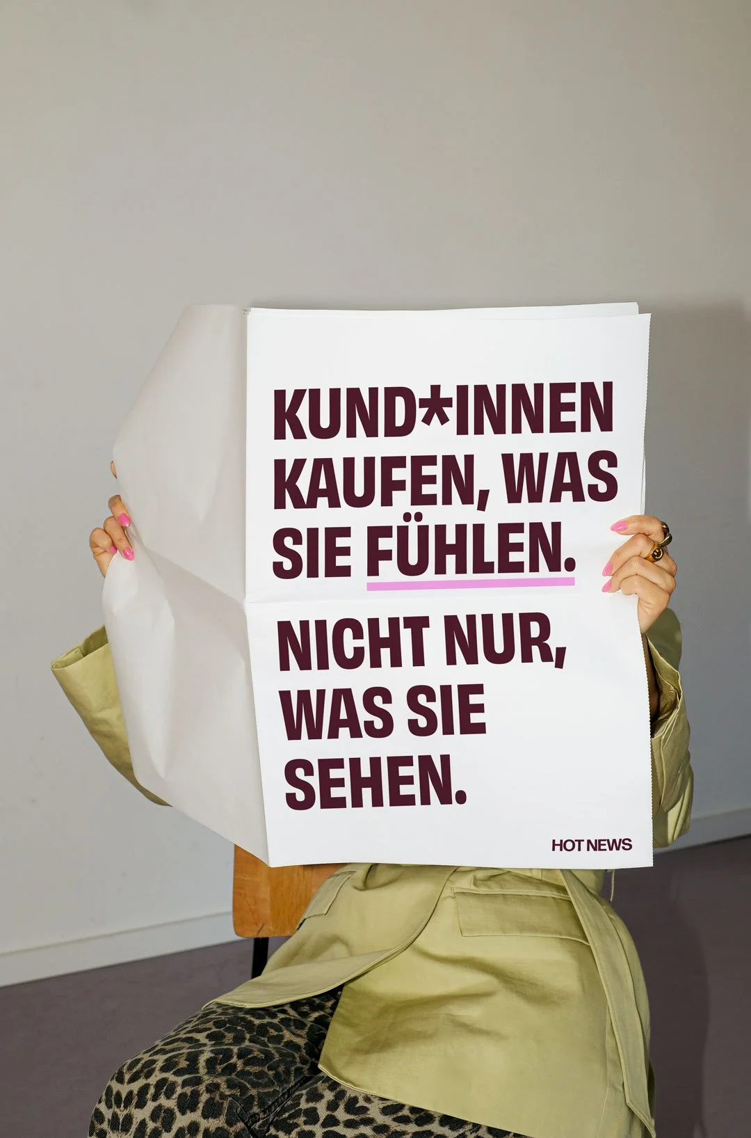Person hält ein Plakat mit der Aufschrift 'KUND*INNEN KAUFEN, WAS SIE FÜHLEN. NICHT NUR, WAS SIE SEHEN'.
