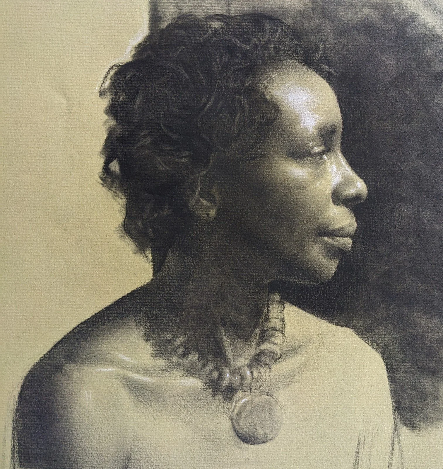 A portrait of an African American woman with curly hair, wearing a beaded necklace with a large pendant, captured in profile.