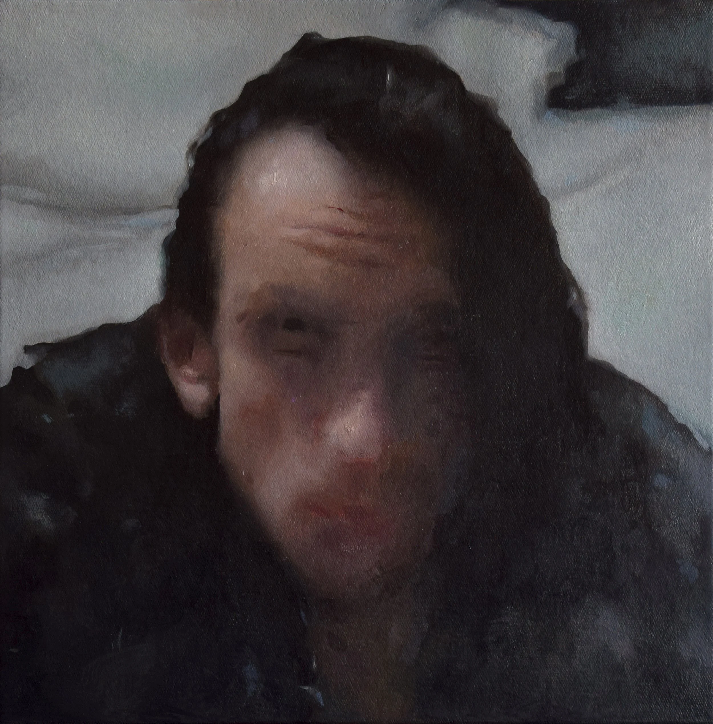 A person with wet hair making a funny face, winking and slightly smiling, lying on a white pillow or bed.