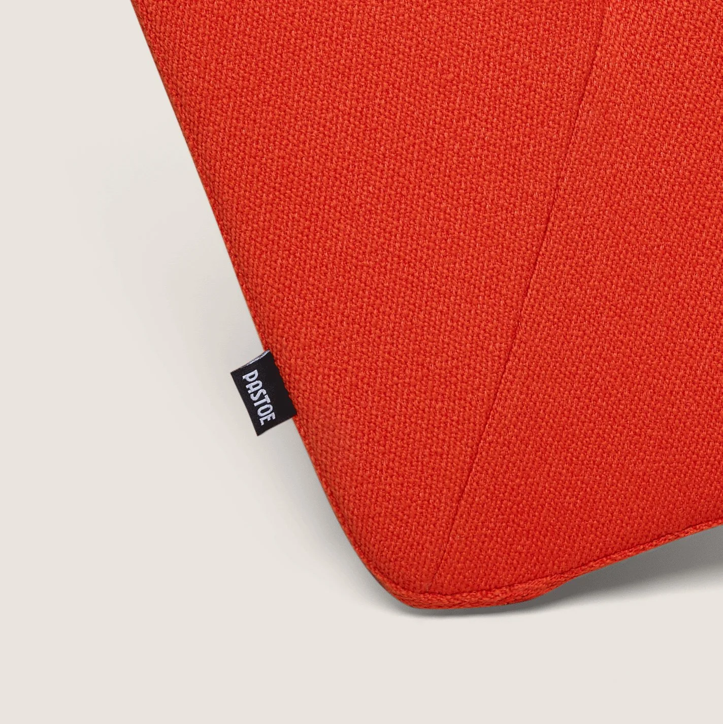 Close-up of an orange textured fabric armchair with rounded edges and a PASTOE label, timeless dutch furniture design, branding and illustration project by Automne Studio.