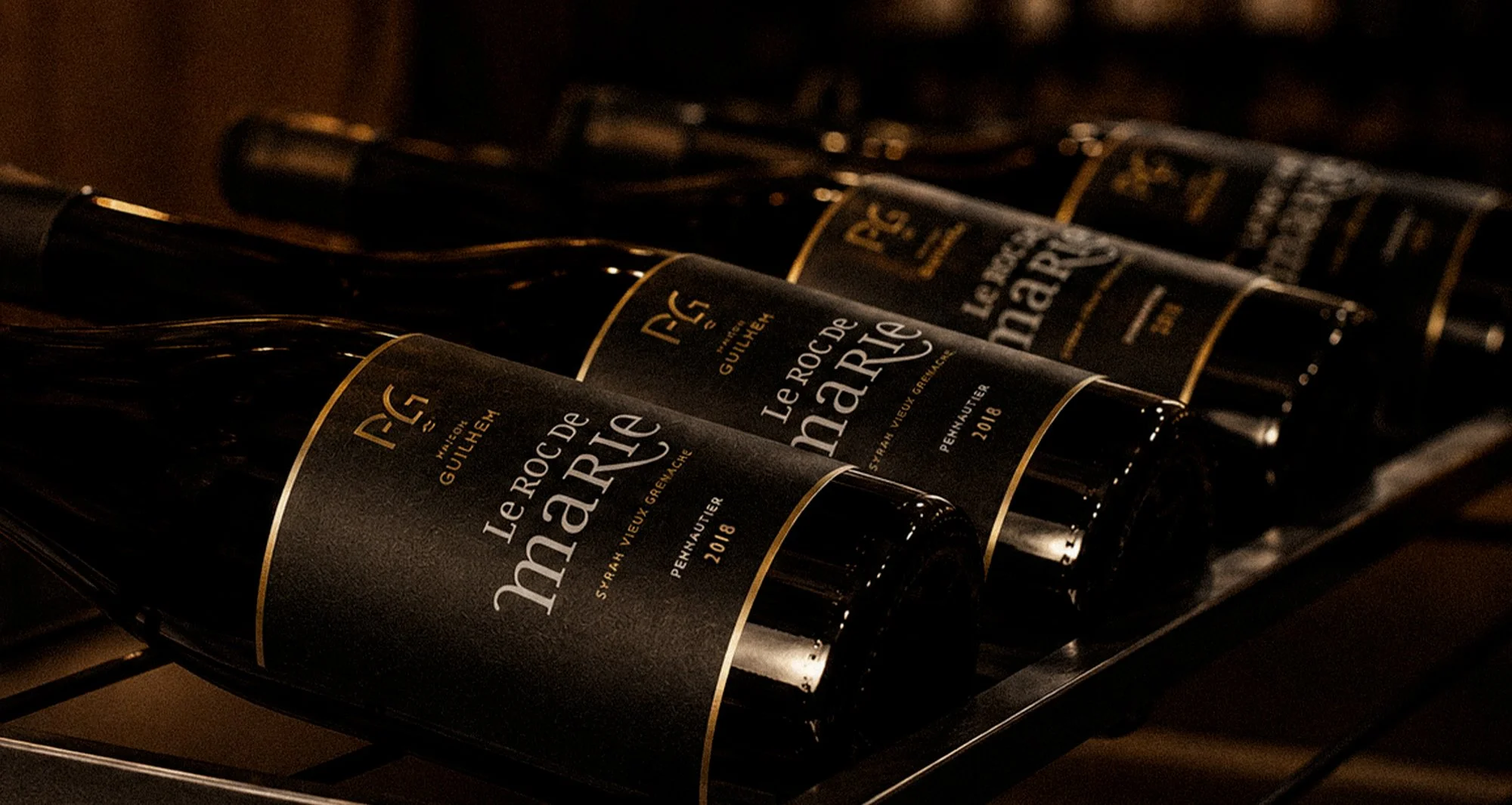 Rows of red wine bottles labeled Le Roc de Marie Syrah Vieux Grenache 2018, Maison Guilhem, French vineyard, branding and editorial project by Automne Studio.