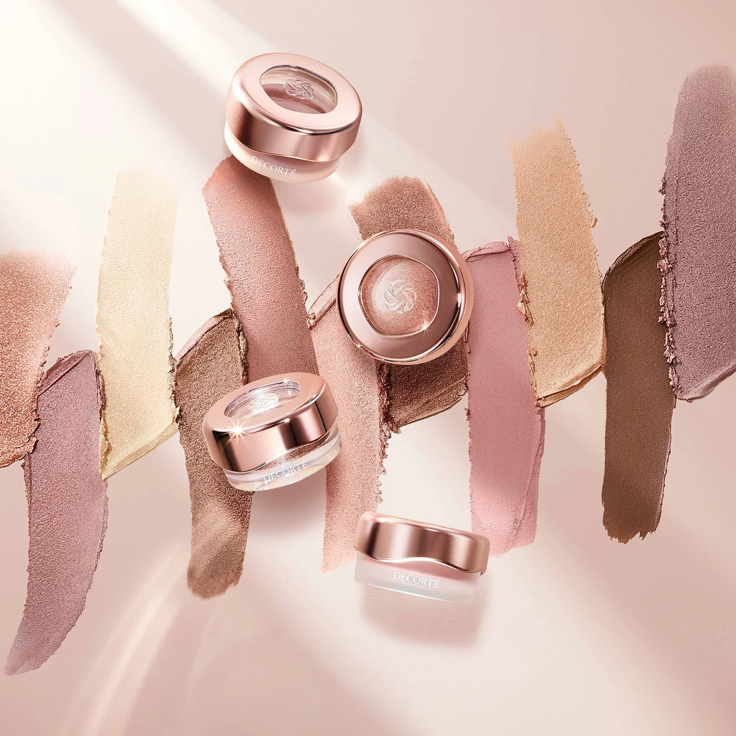 DECORTÉ rose-gold makeup compacts surrounded by nude and pink eyeshadow swatches, Marcel Wanders x Decorté Emblem, branding by Automne Studio.