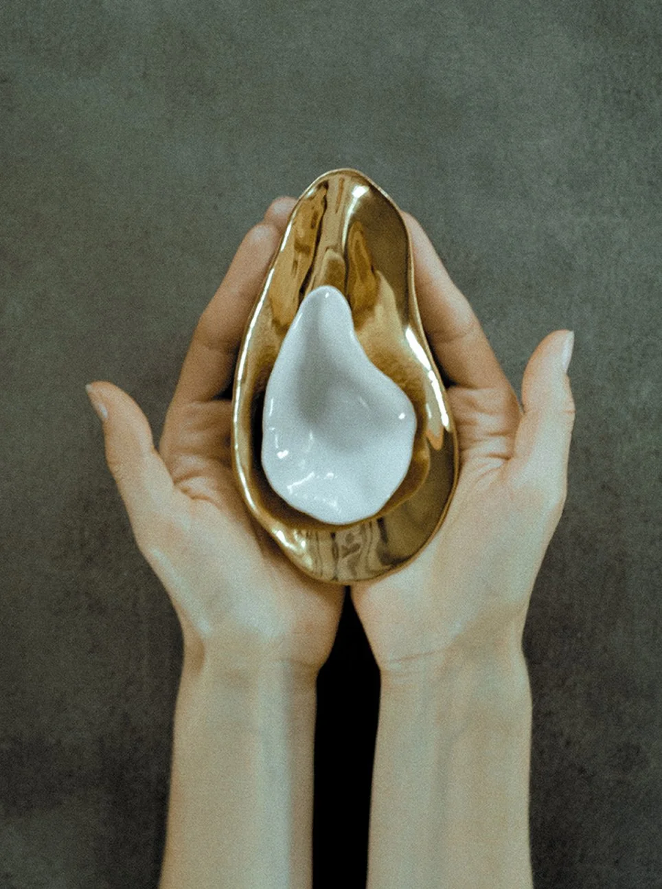 Hands holding a gold-toned Indulge plate by Sarah-Linda, sensual tableware, branding, web design and editorial project by Automne Studio.